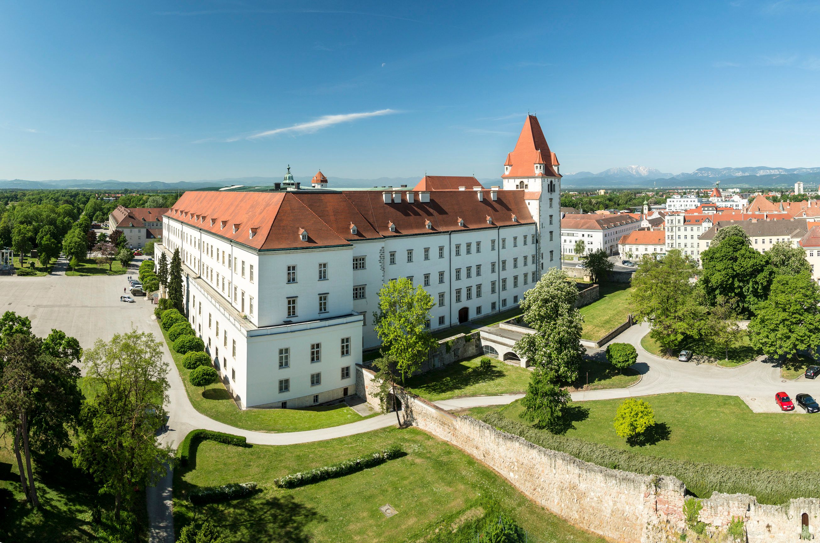 Aerial view of the Theresian Military Academy in Austria with red roof and surrounding greenery.