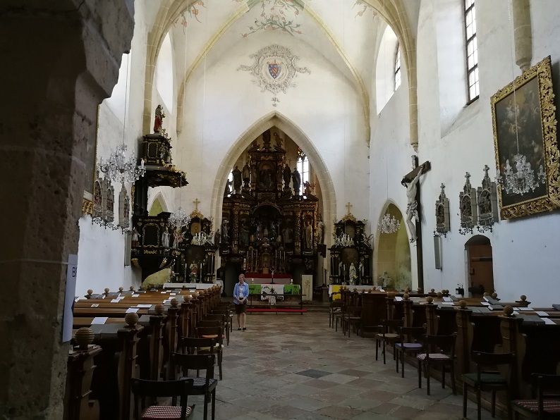 Interior view of a pilgrimage church with altar, benches and religious works of art.