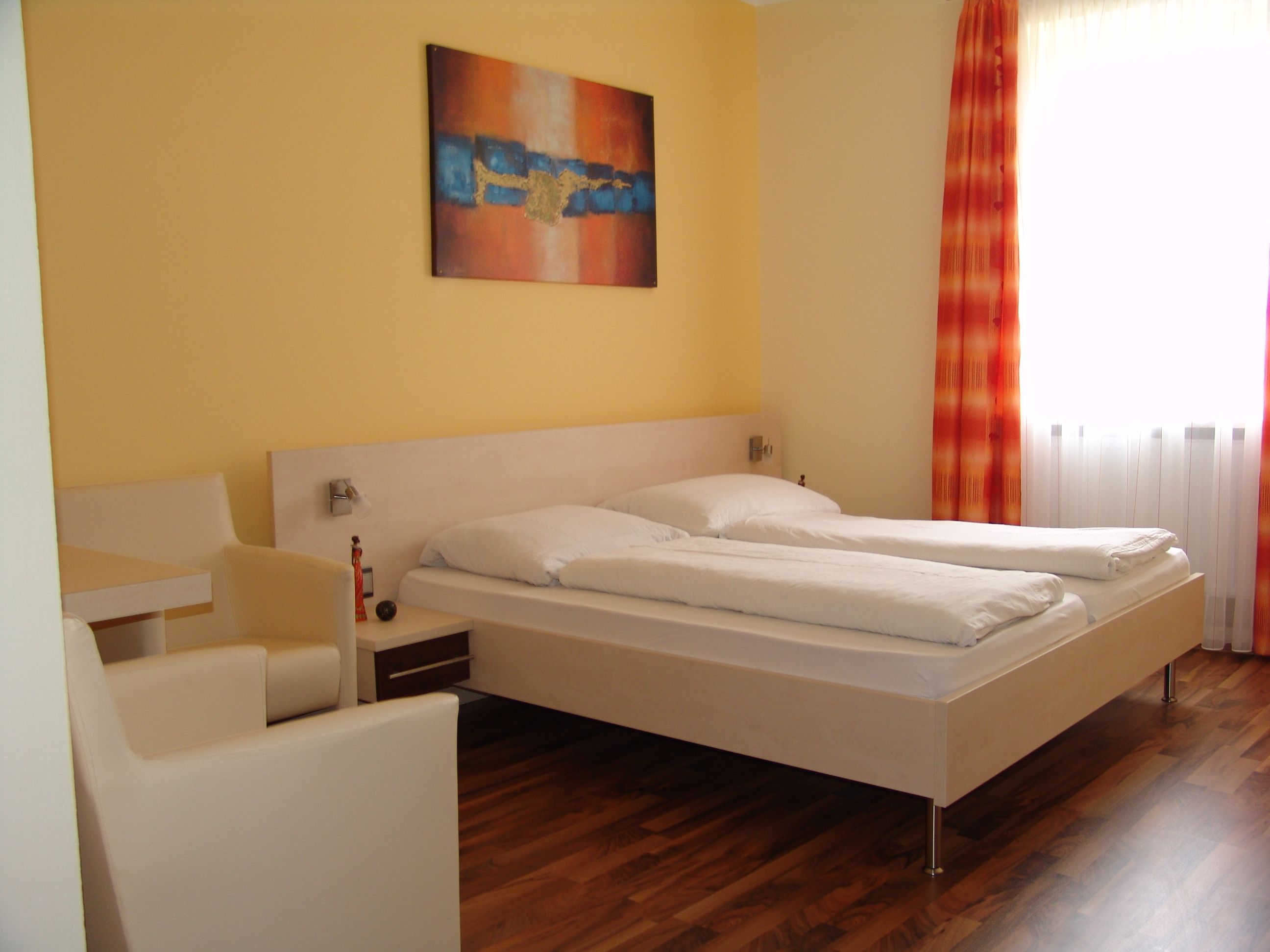 A modern hotel room with a double bed, yellow walls and an abstract painting.