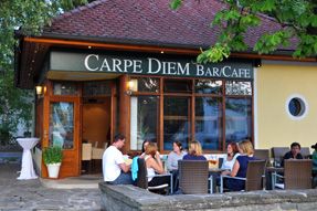 Exterior view of a café called Carpe Diem, people sitting at outdoor tables.