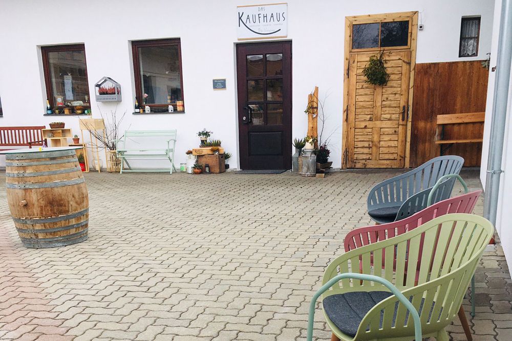 Seating area in front of a department store with colorful chairs and a barrel.