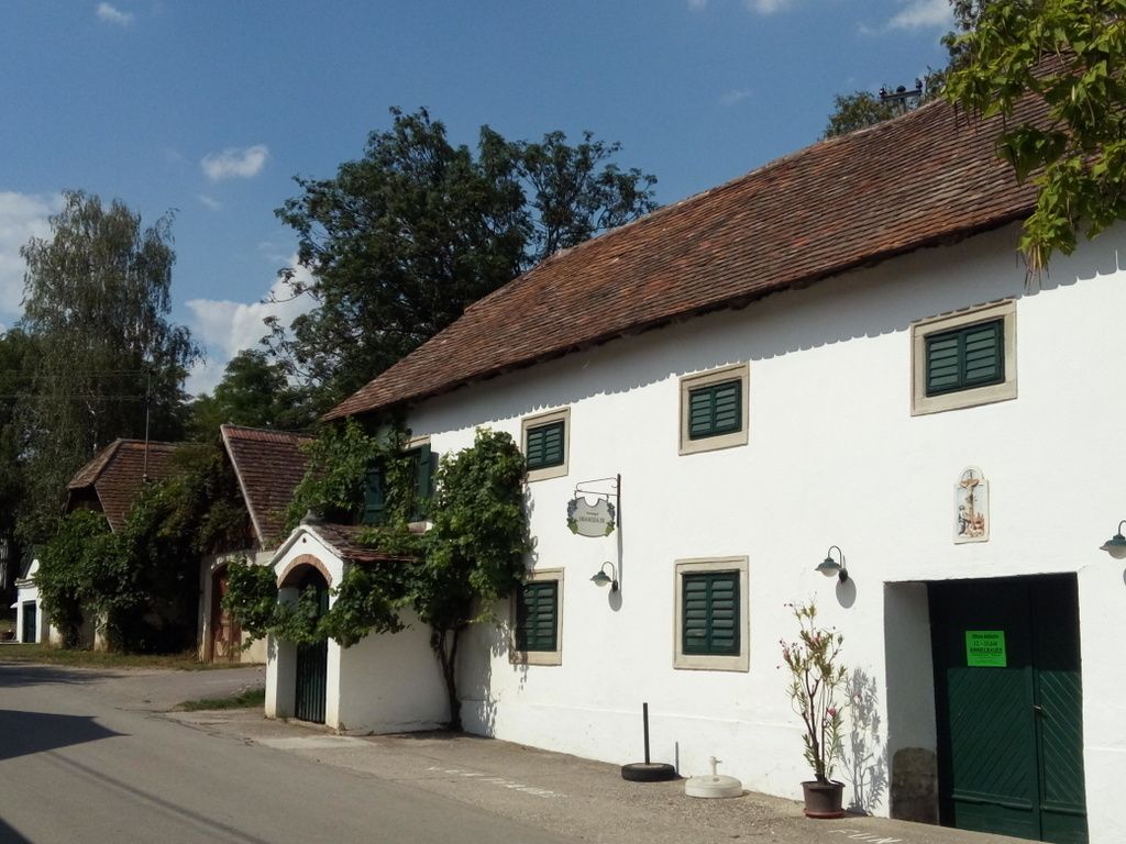 White building with green shutters and an open door on a street.