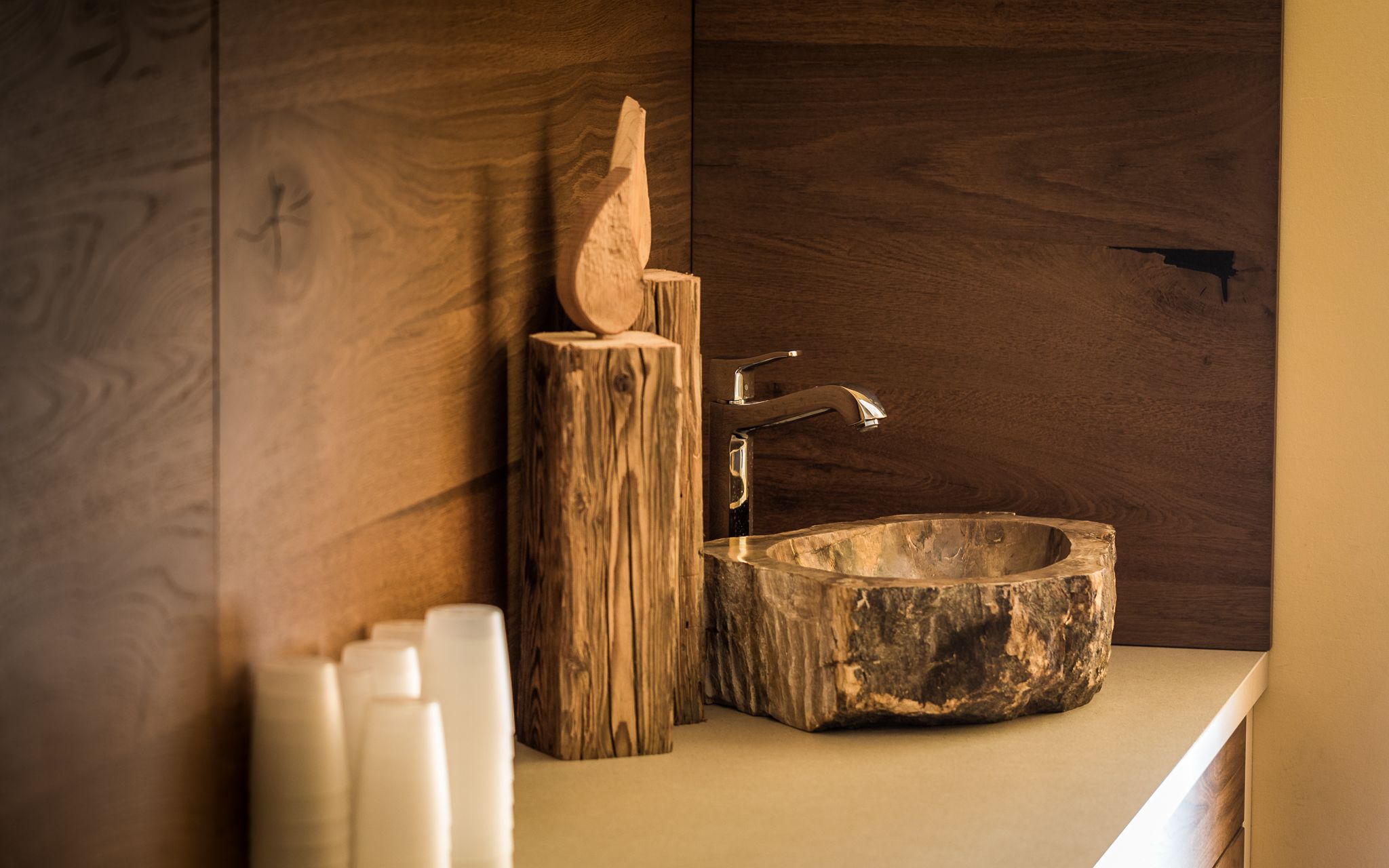 Rustic wooden washbasin with tap and wooden decor.