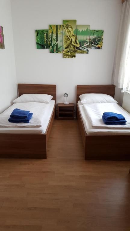 Two single beds in a room with wall decoration and blue towels.