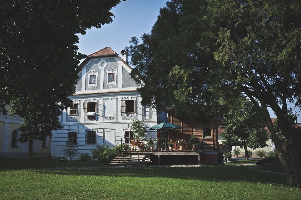 Historic building with terrace and trees in the foreground.