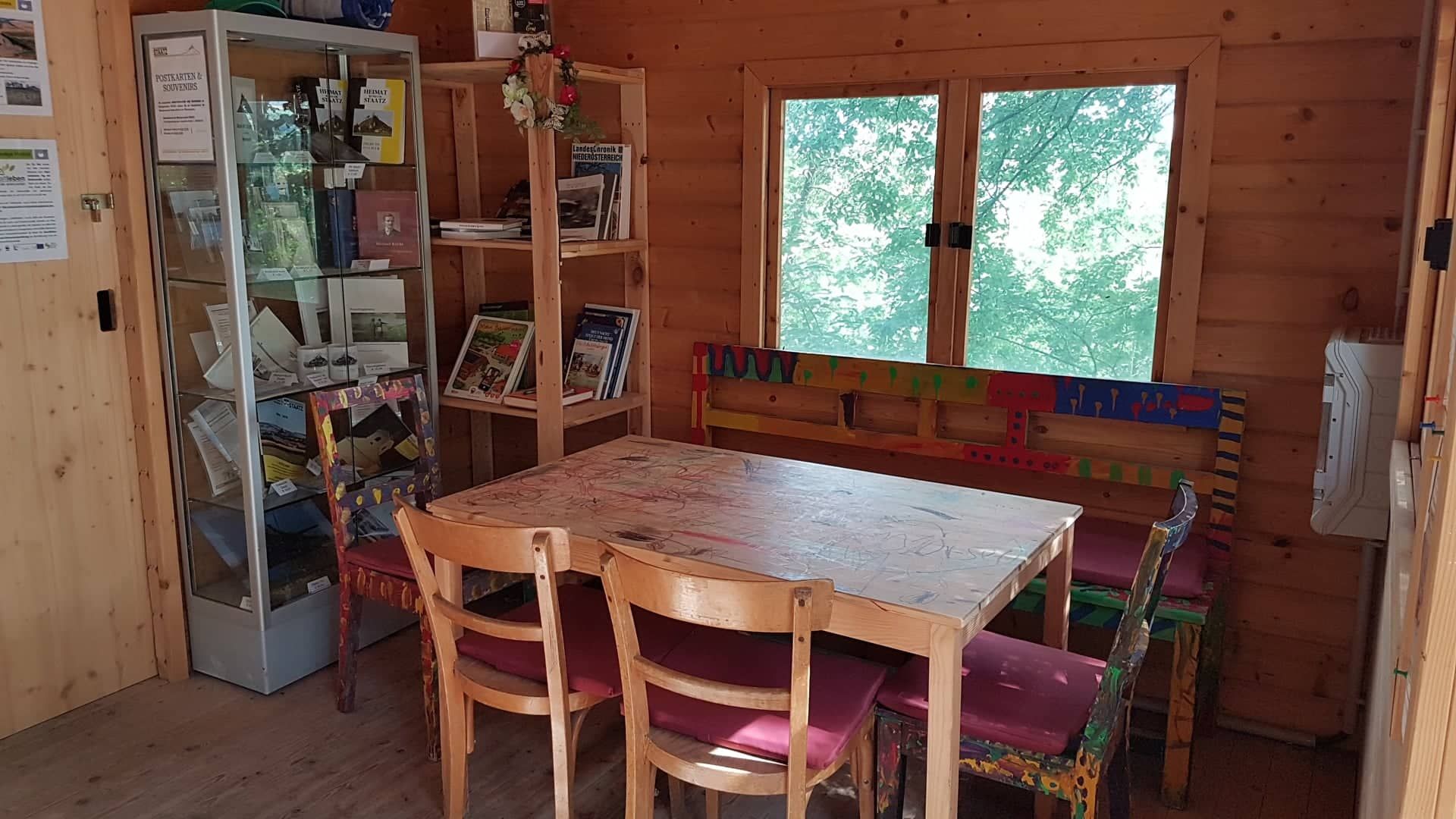 Interior view of a wooden room with table, chairs and bookshelves.