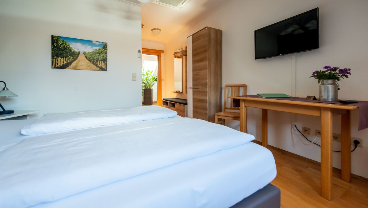 Comfortable hotel room with double bed, wooden furniture, TV and plants.