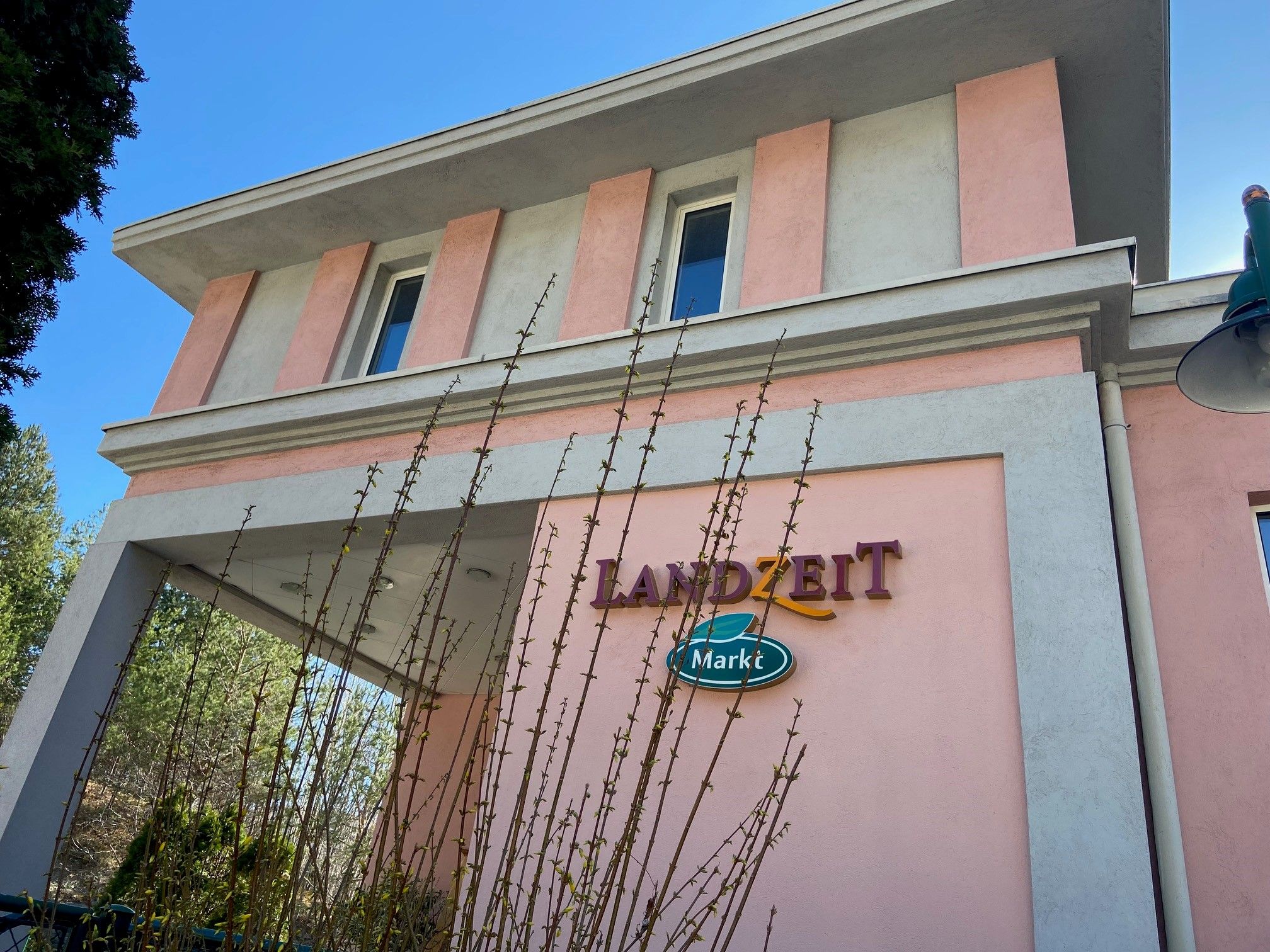 Building with pink and gray facade, lettering 'Landzeit Markt'.
