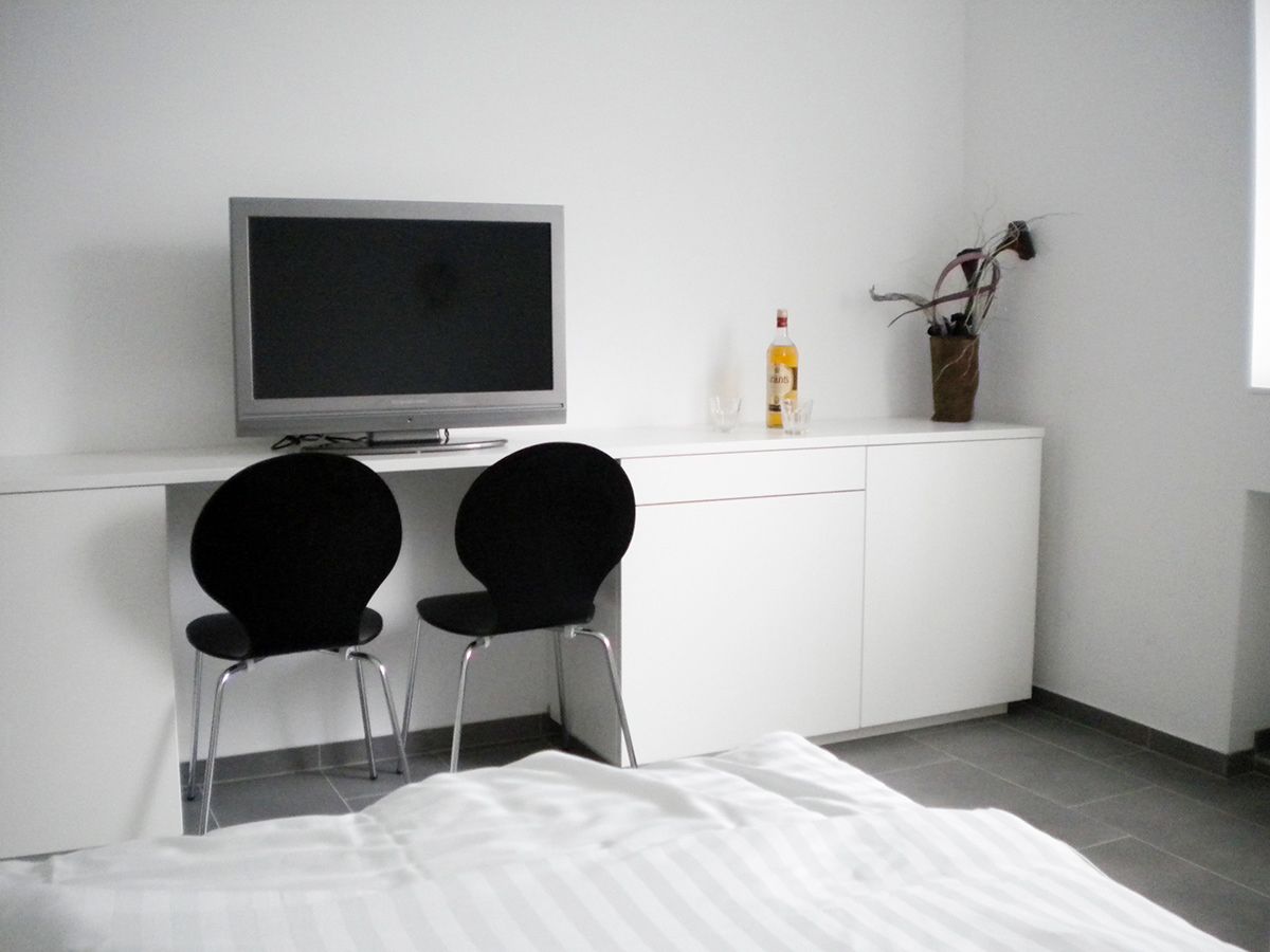 Modern room with TV, two black chairs and white wardrobe.