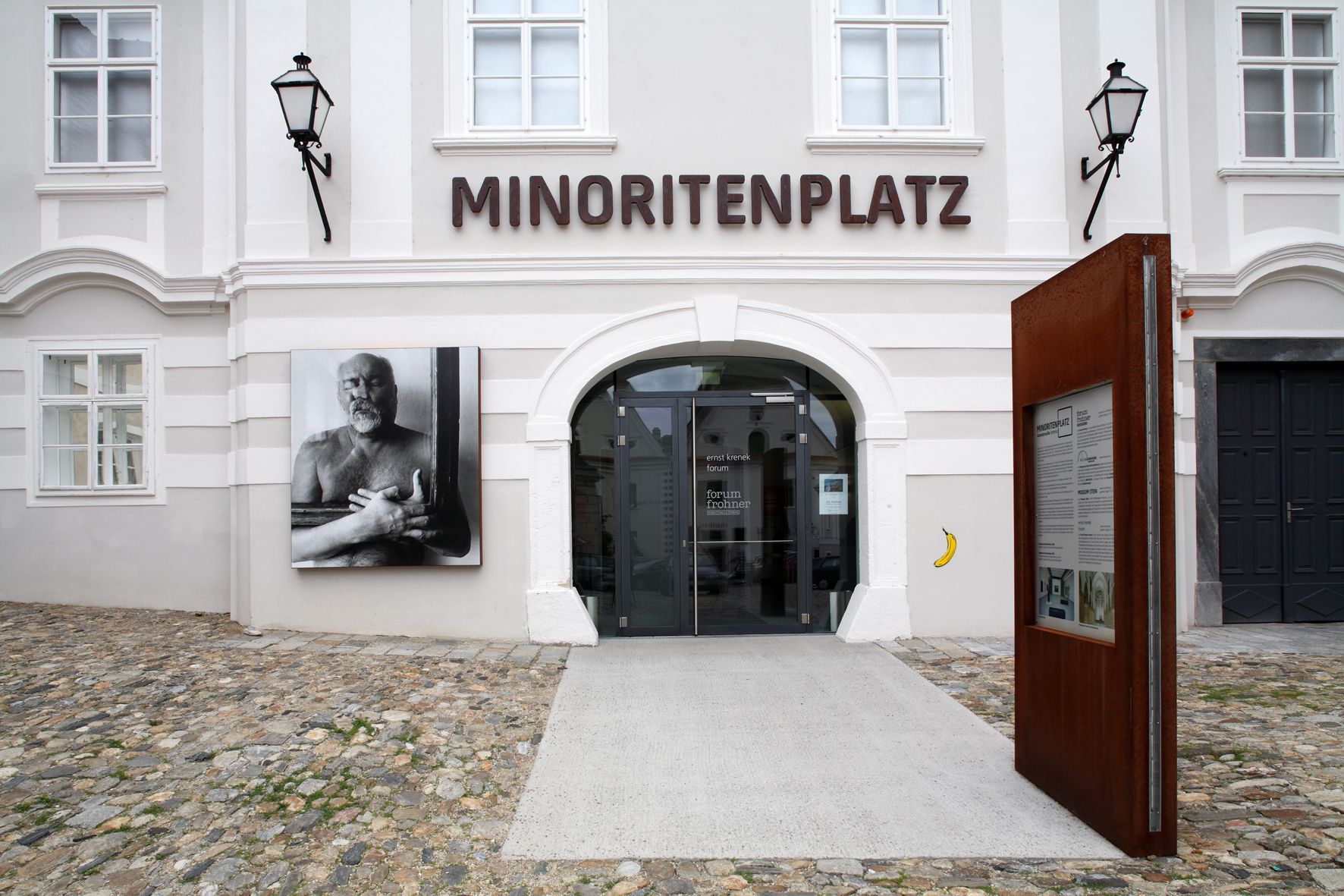 Entrance to Forum Frohner on Minoritenplatz with art photo and information board.