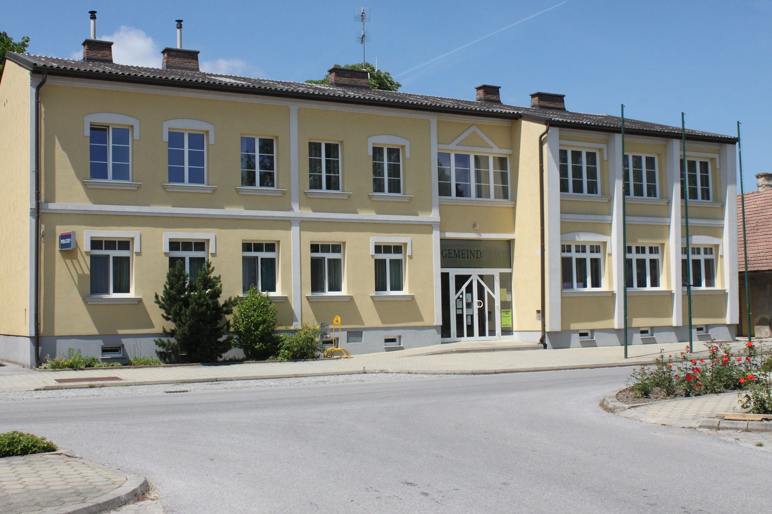 Yellow building with the inscription 'Gemeindeamt' and several windows.