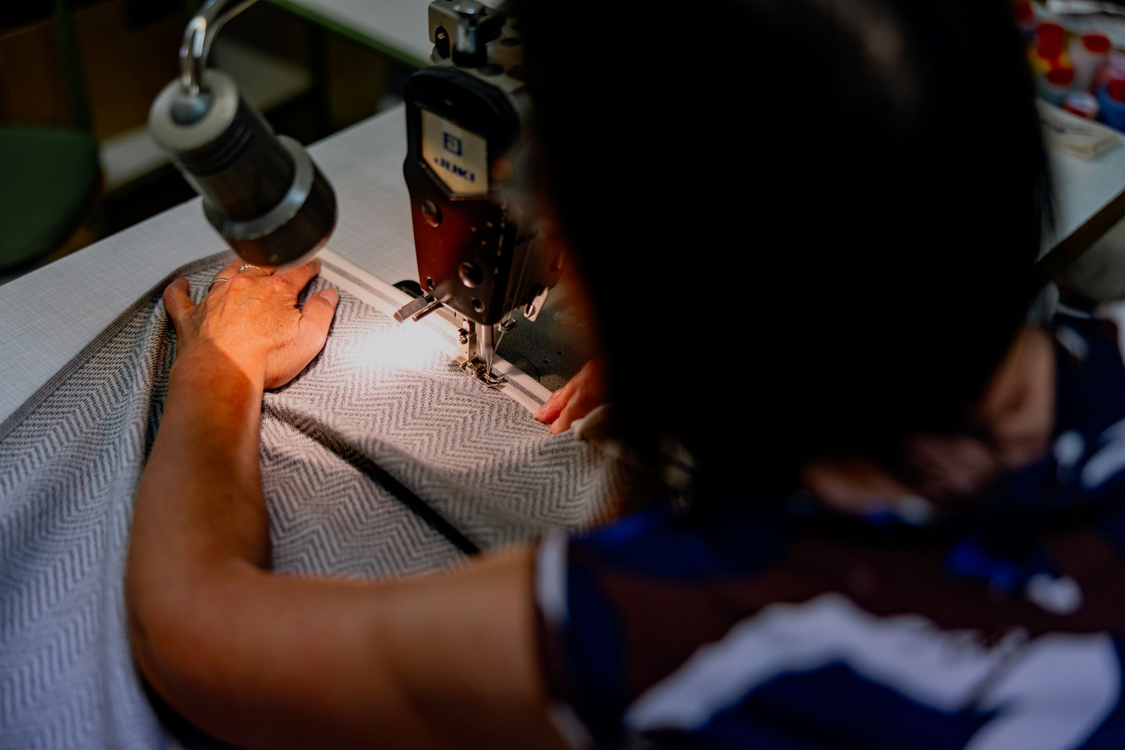 Person sews fabric with sewing machine.