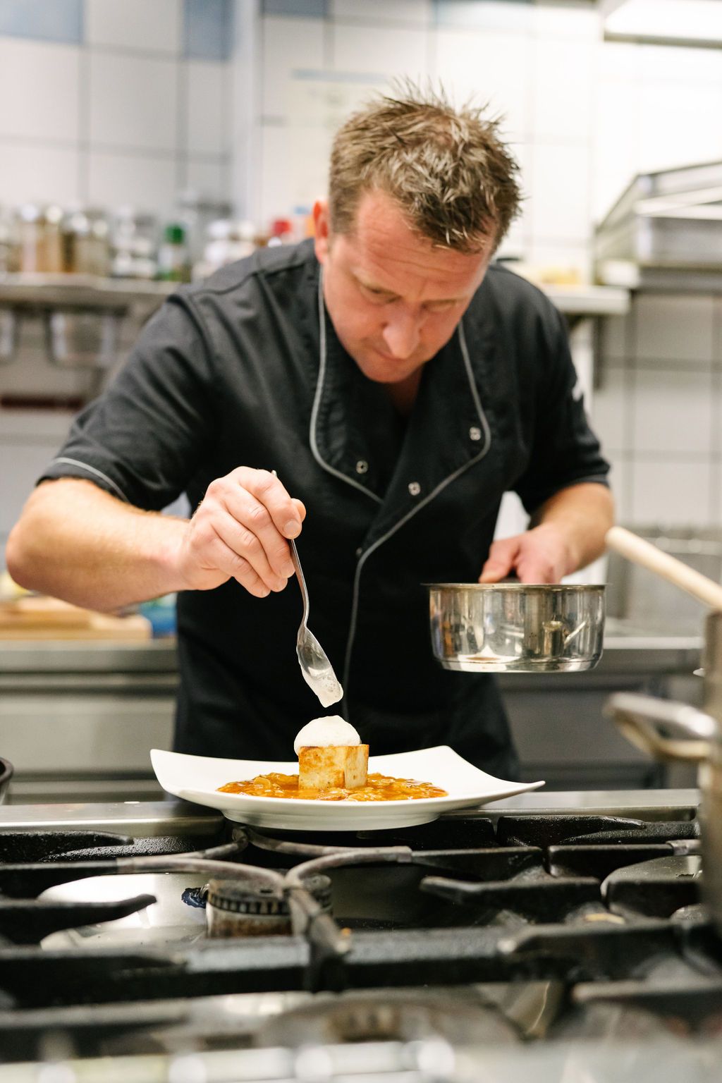 A chef decorates a dish in a professional kitchen.