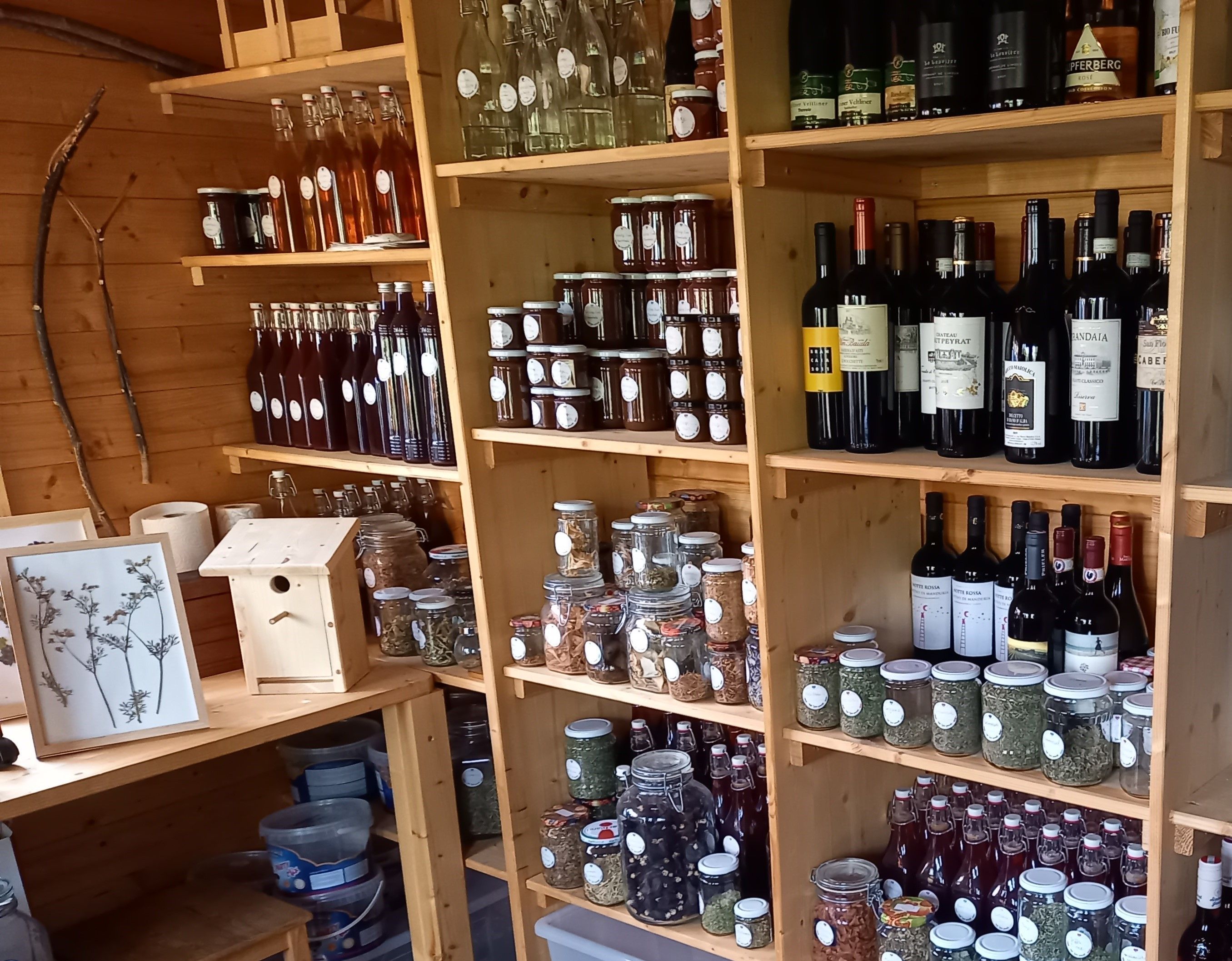 Shelves with bottles, glasses and wine in a wooden store.