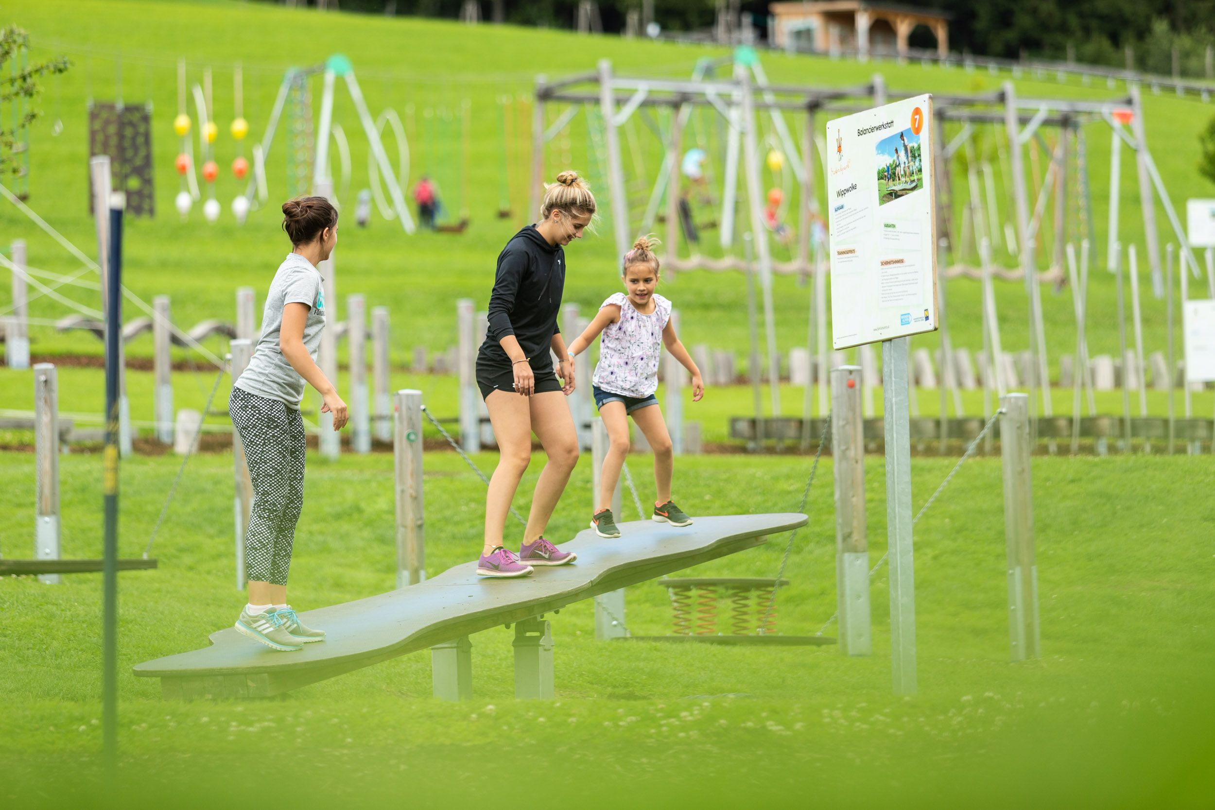 Three people balancing on a seesaw in the St. Corona motor skills park.