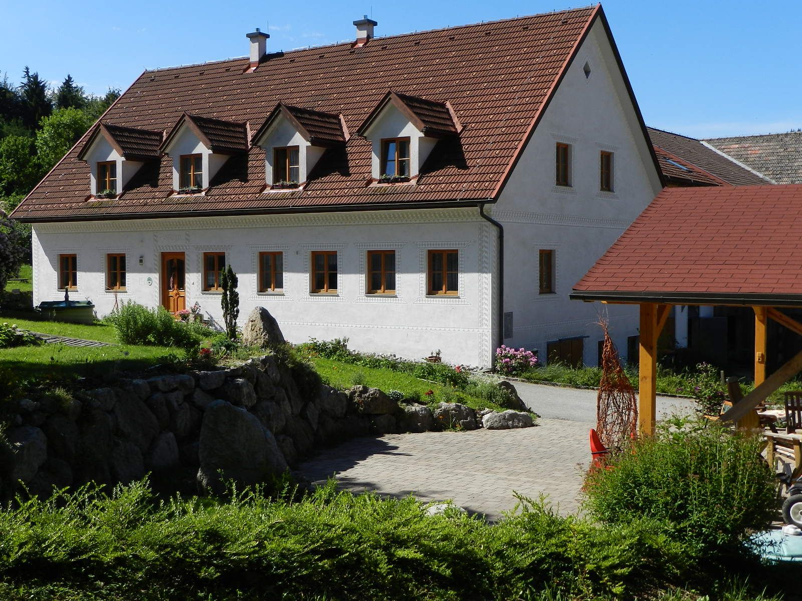 A traditional white country house with a red roof and garden.