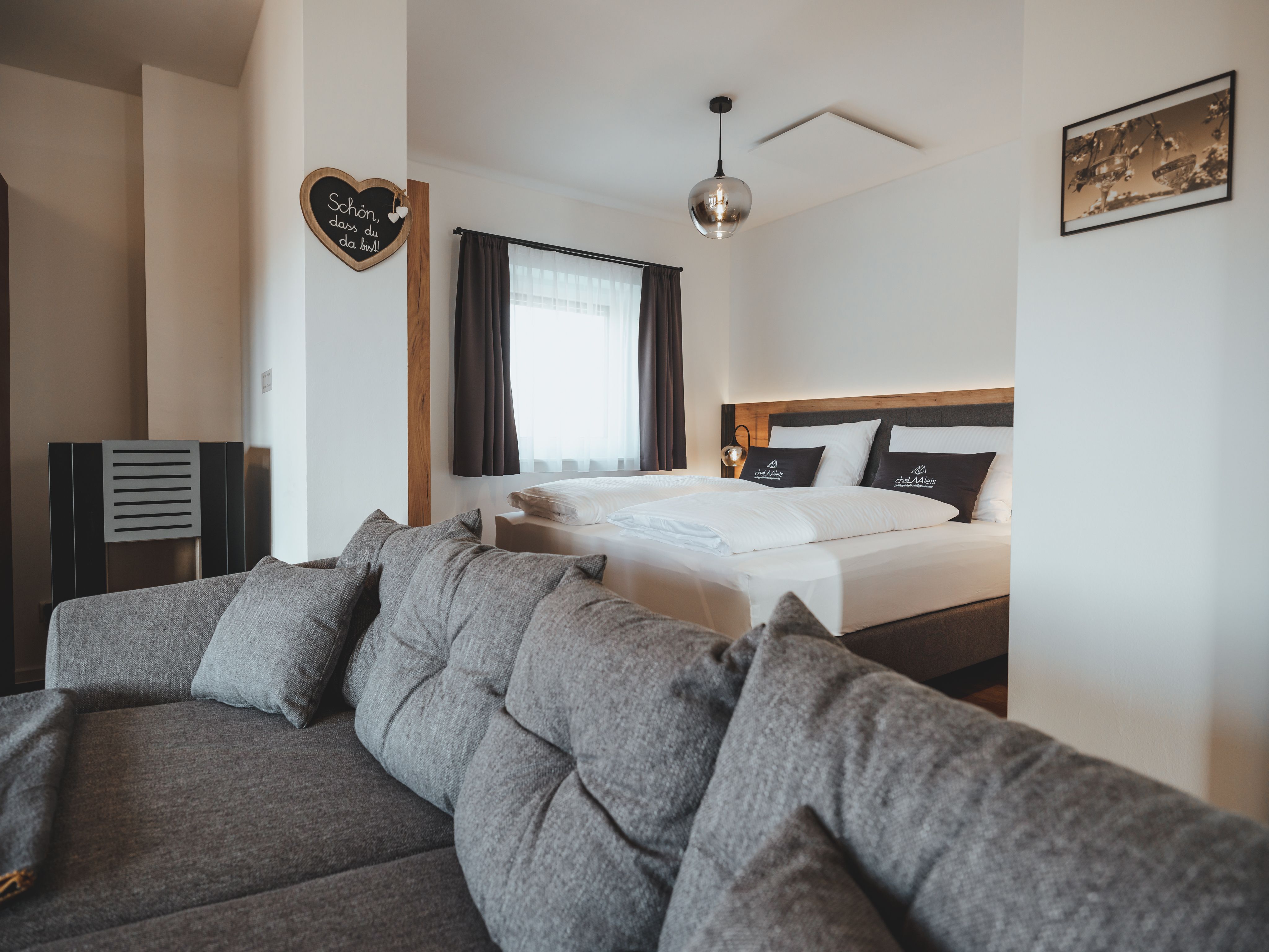 Modern furnished bedroom with gray sofa and double bed.