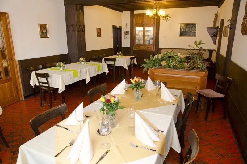 Interior view of a traditional restaurant with laid tables and plants.