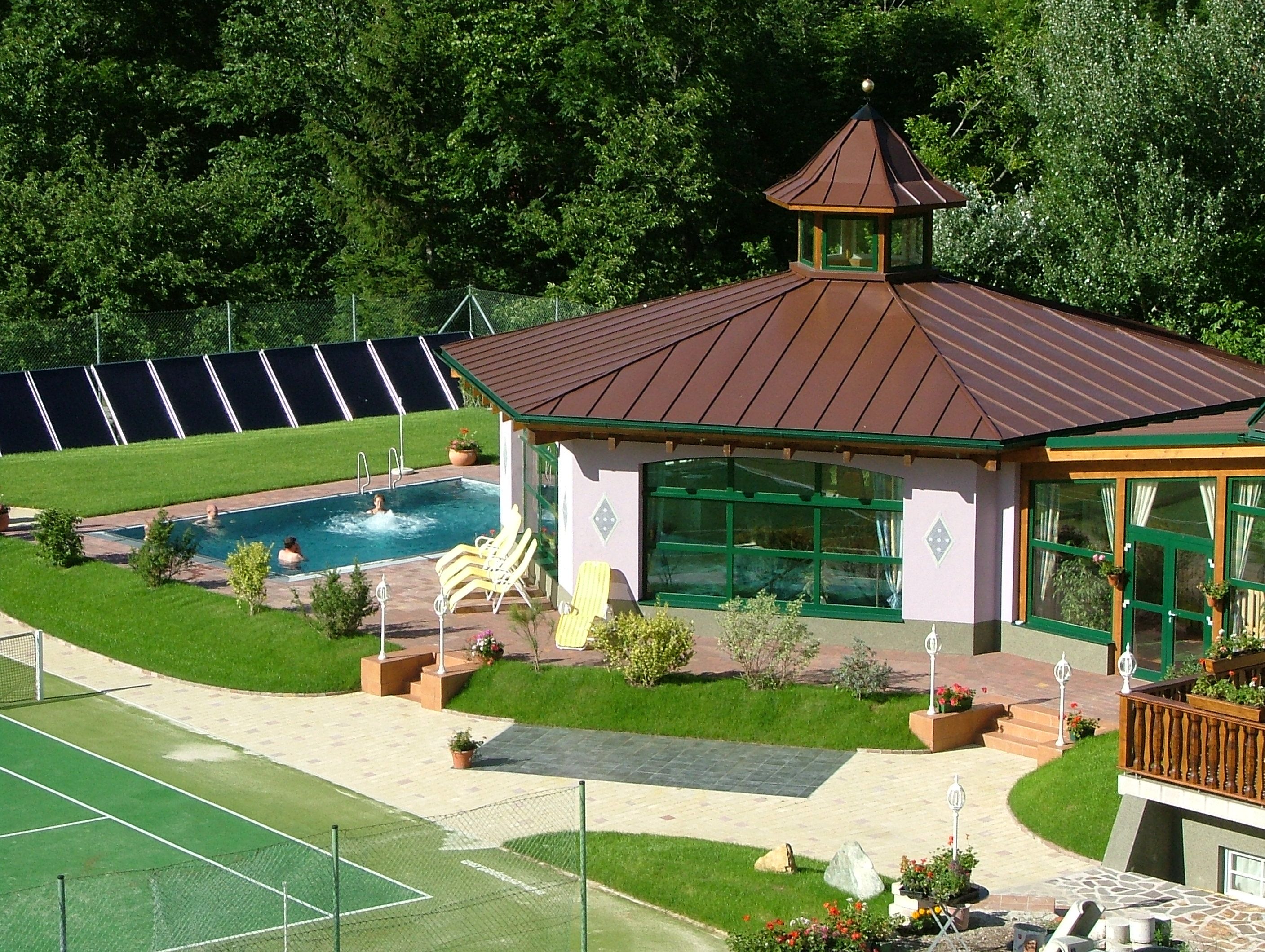 Exterior view of a wellness area with pool and pavilion surrounded by greenery.