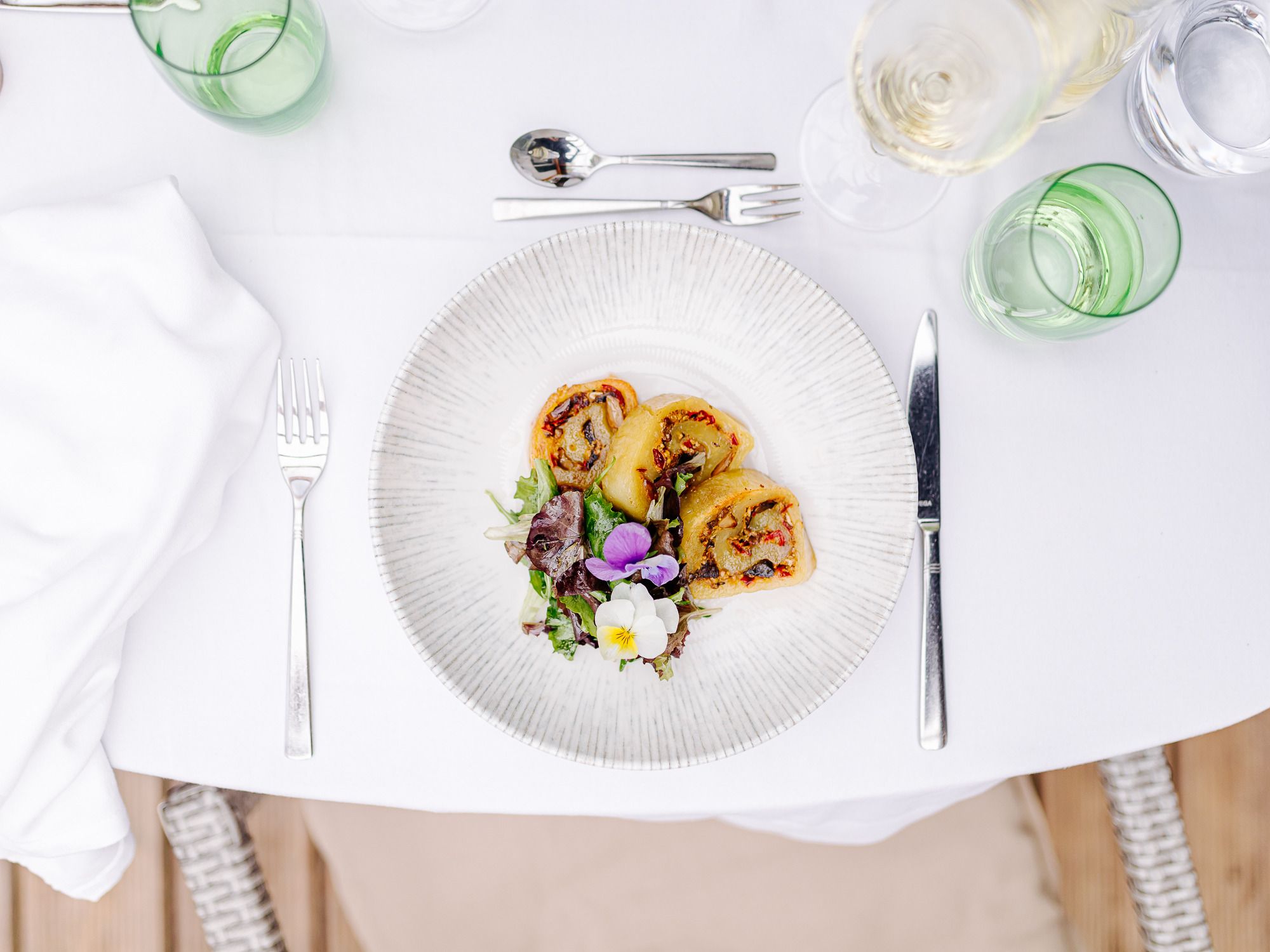 A plate of stuffed potato roulade and salad on a laid table.