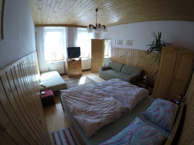 Cozy bedroom with double bed, sofa, TV and wooden furniture in a vacation apartment.