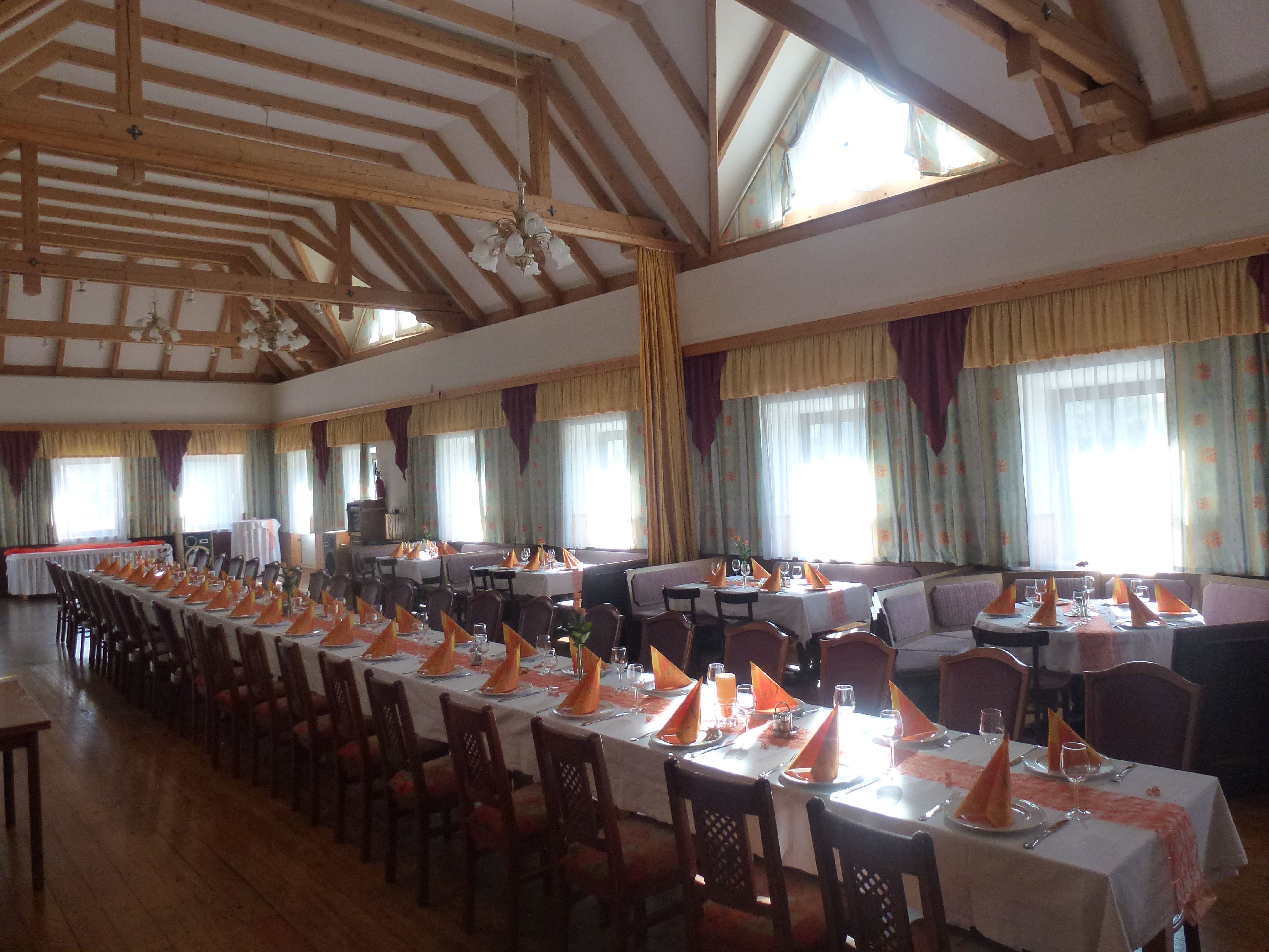 Interior view of an inn with covered tables and wooden beamed ceiling.