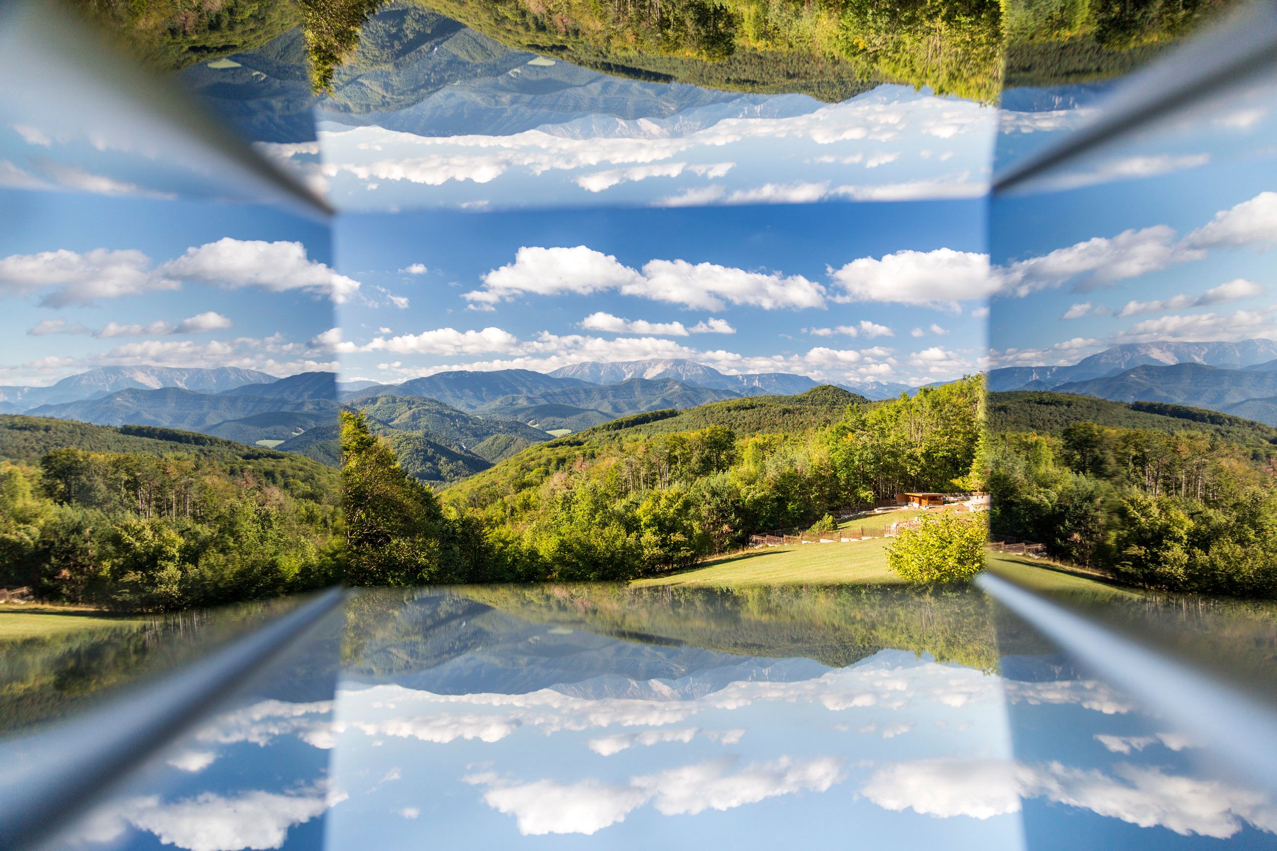 Reflection of a mountain landscape with blue sky and clouds.