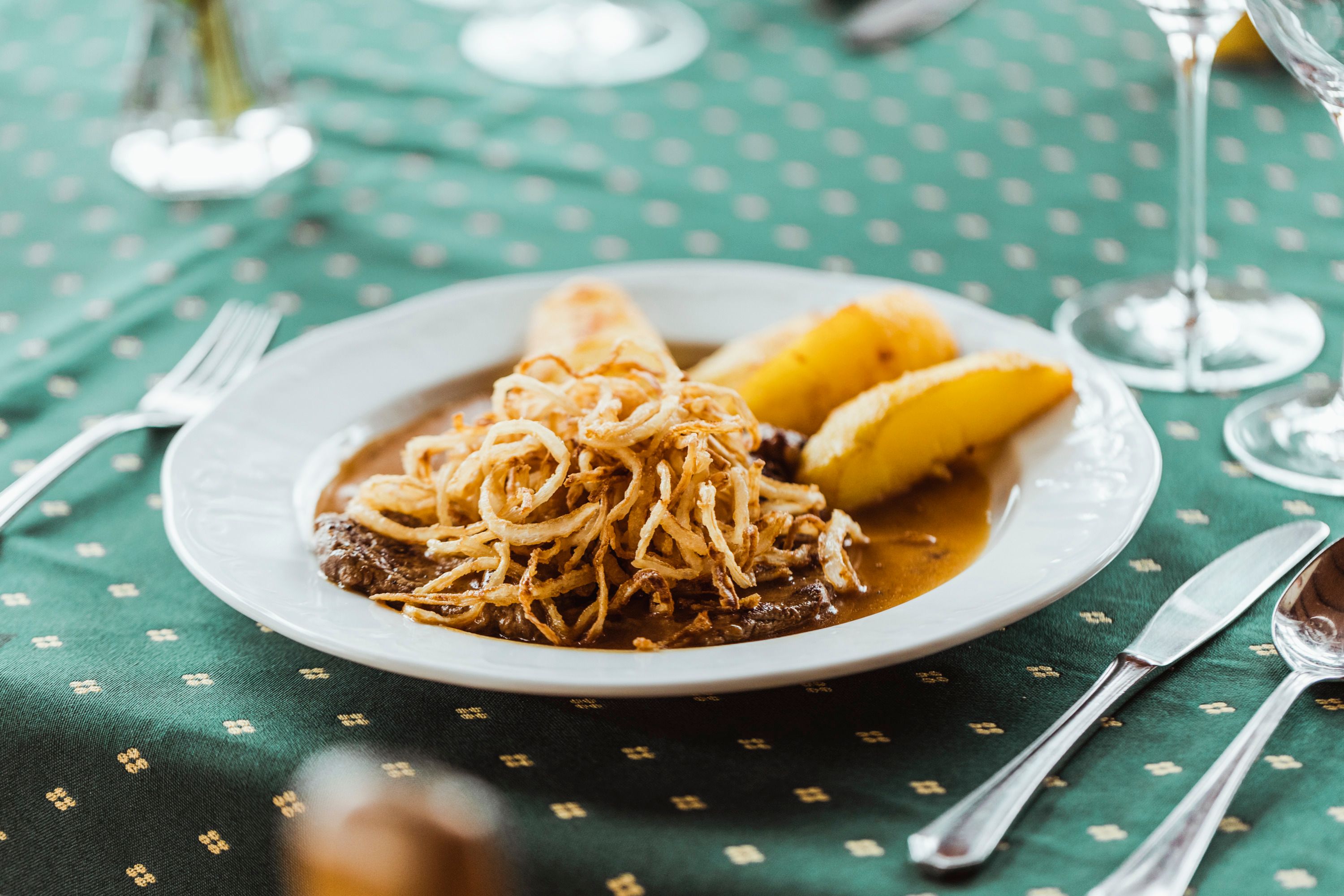 A plate of roast onions and roast potatoes on a green table.