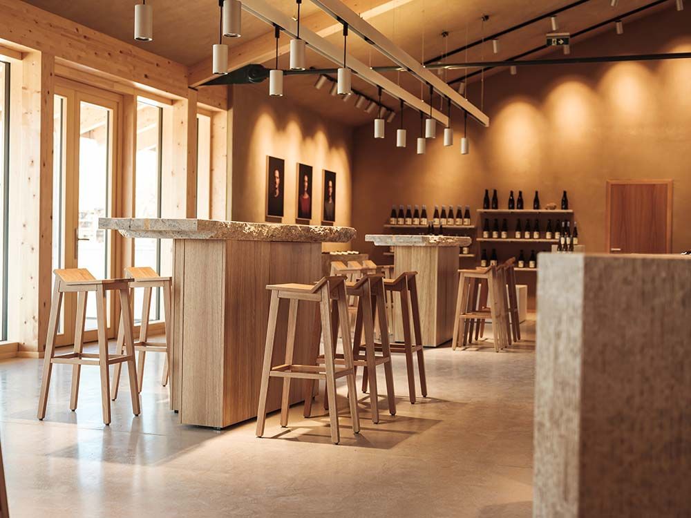 Interior view of a modern tasting room with wooden furniture and wine bottle racks.