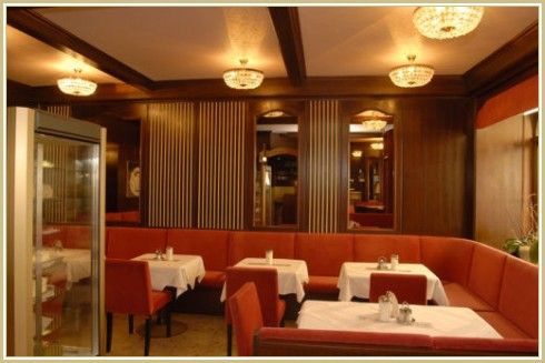 Interior view of an elegant restaurant with red benches and white tablecloths.