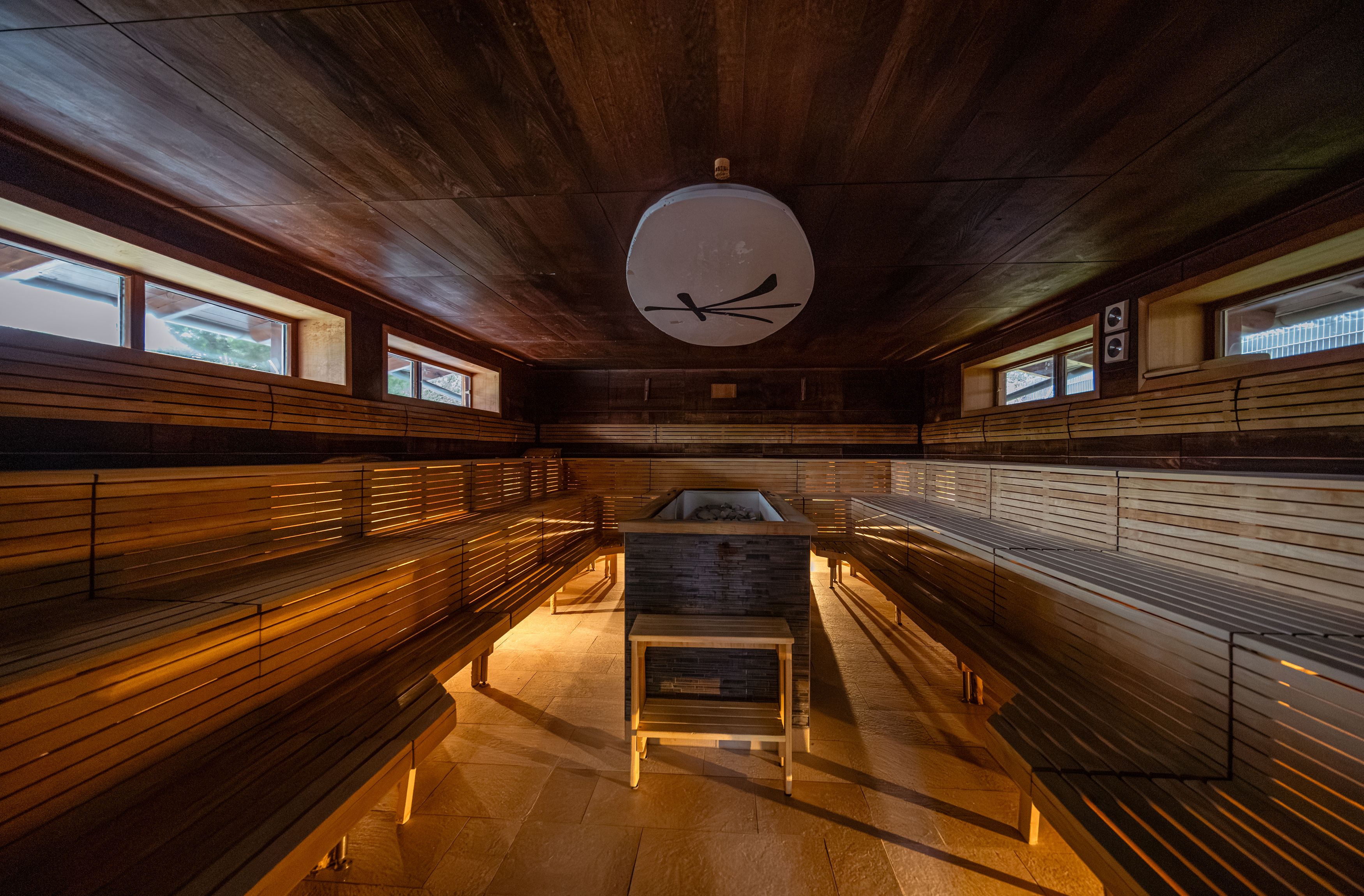 Interior view of a sauna with wooden benches and central stove.