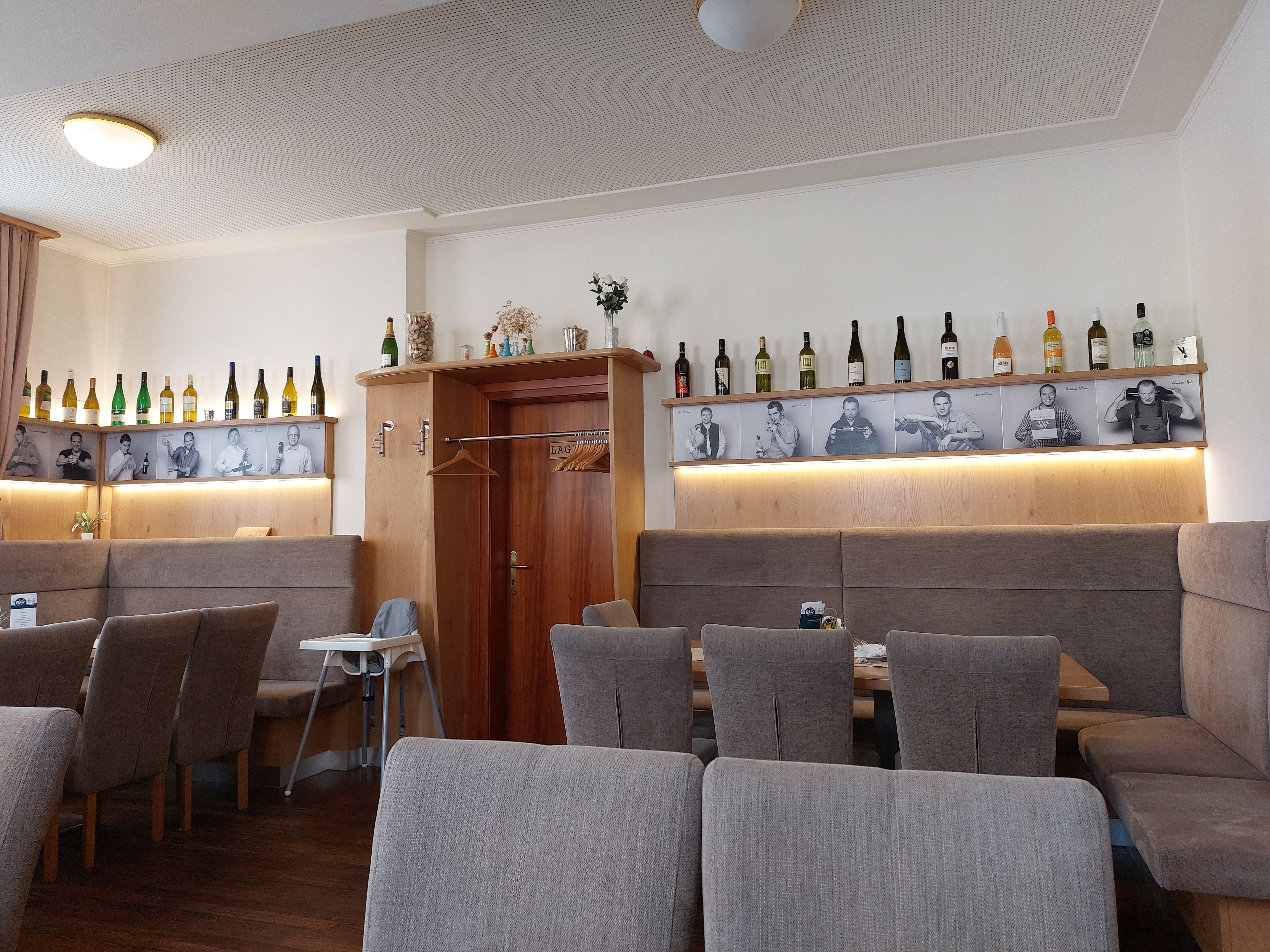 Interior view of a restaurant with wine bottles and black and white photos on the wall.