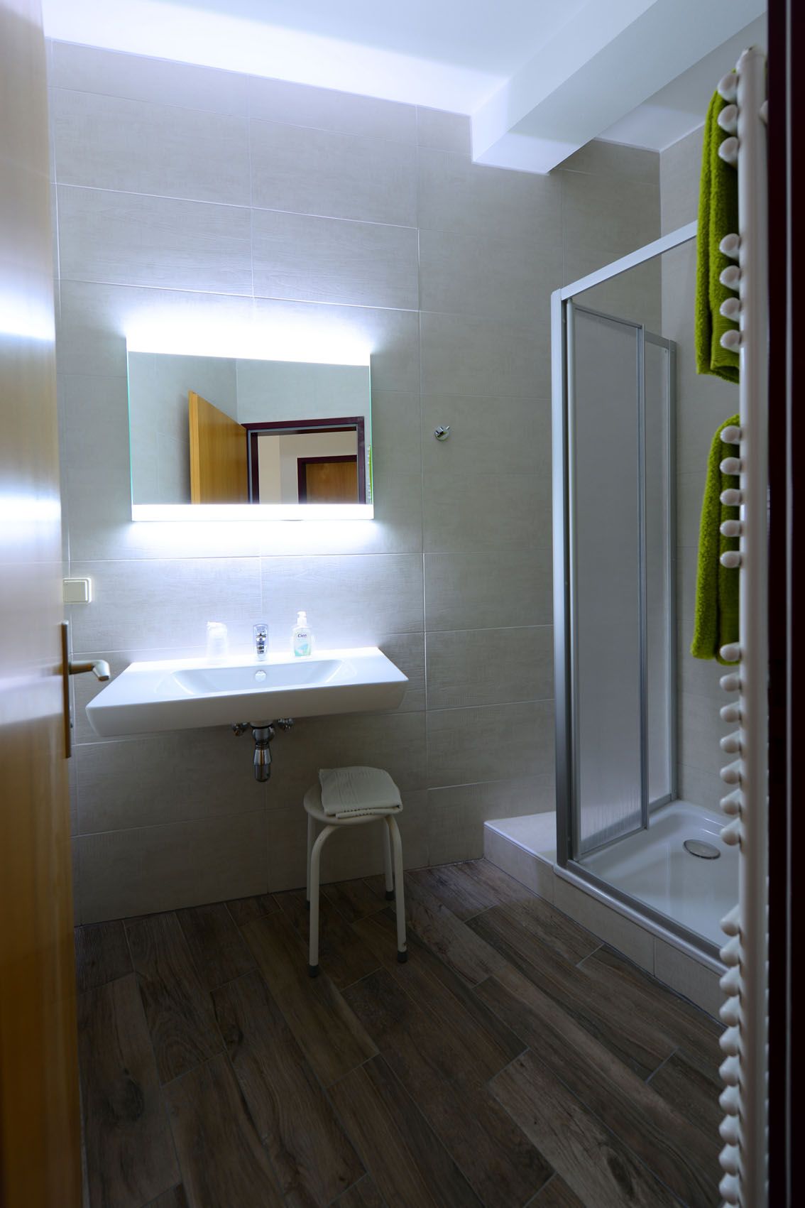 Modern bathroom with washbasin, illuminated mirror and shower.