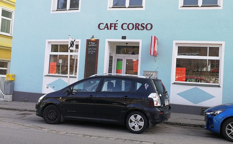Exterior view of Café Corso with parked car in front.