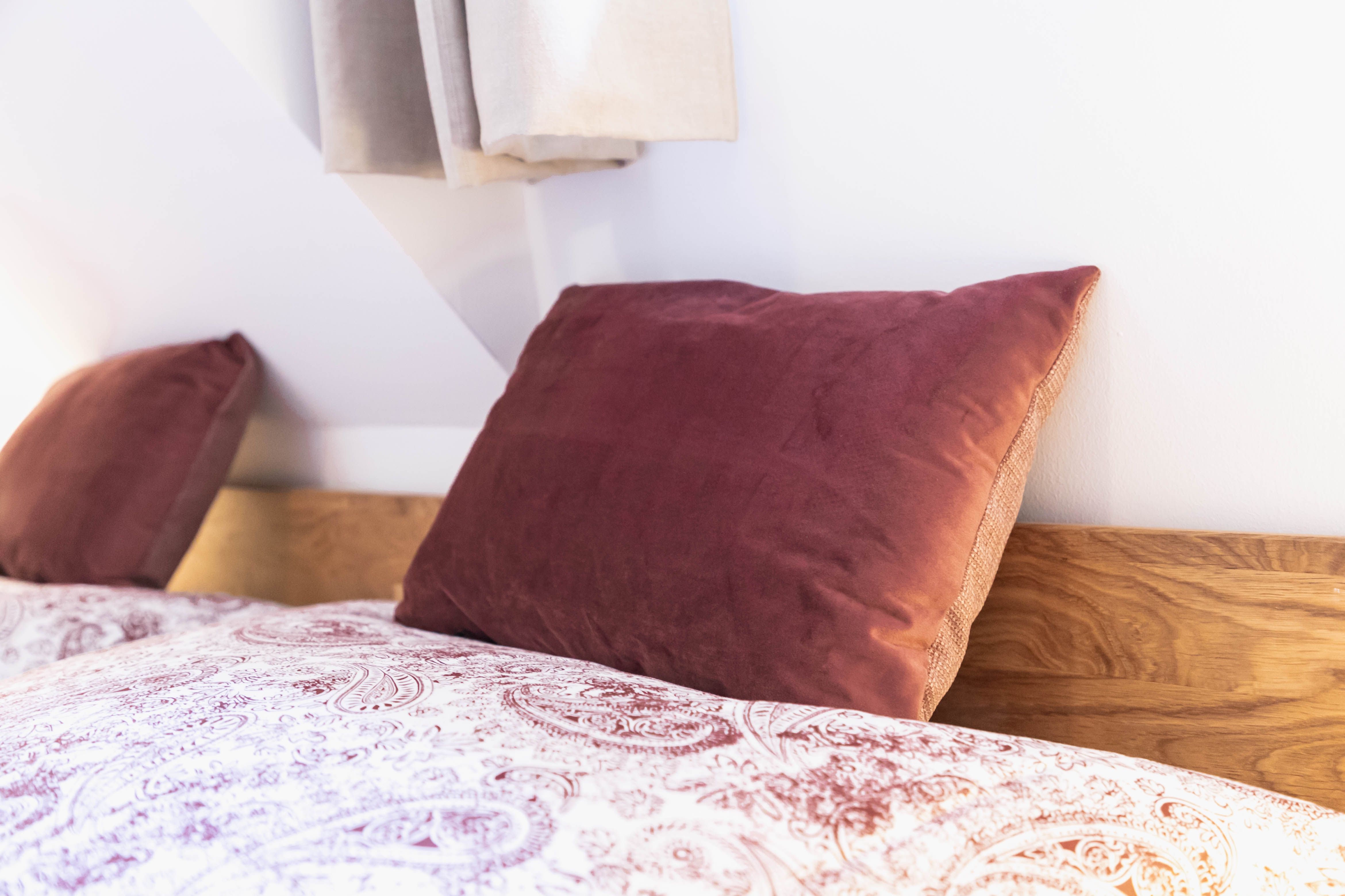 Close-up of a bed with red pillows and patterned bed linen.
