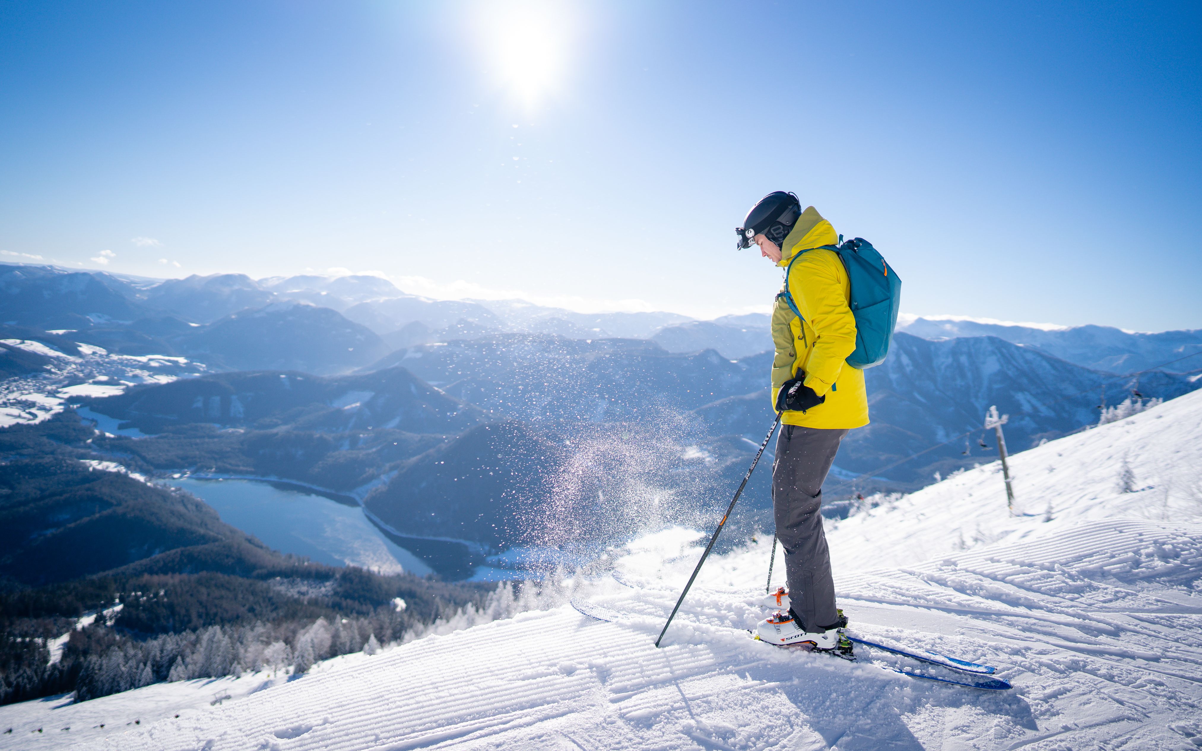 Snowboarder jumping over a yellow obstacle in the Gemeindealpe snowpark in the sunshine.
