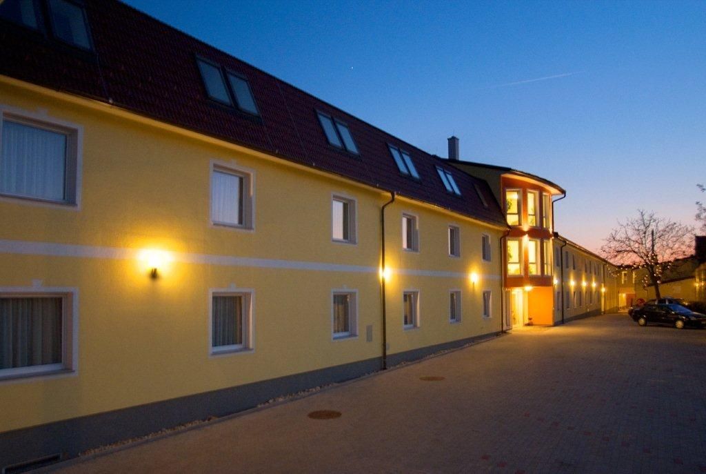 Yellow hotel building at dusk with illuminated windows and entrance.