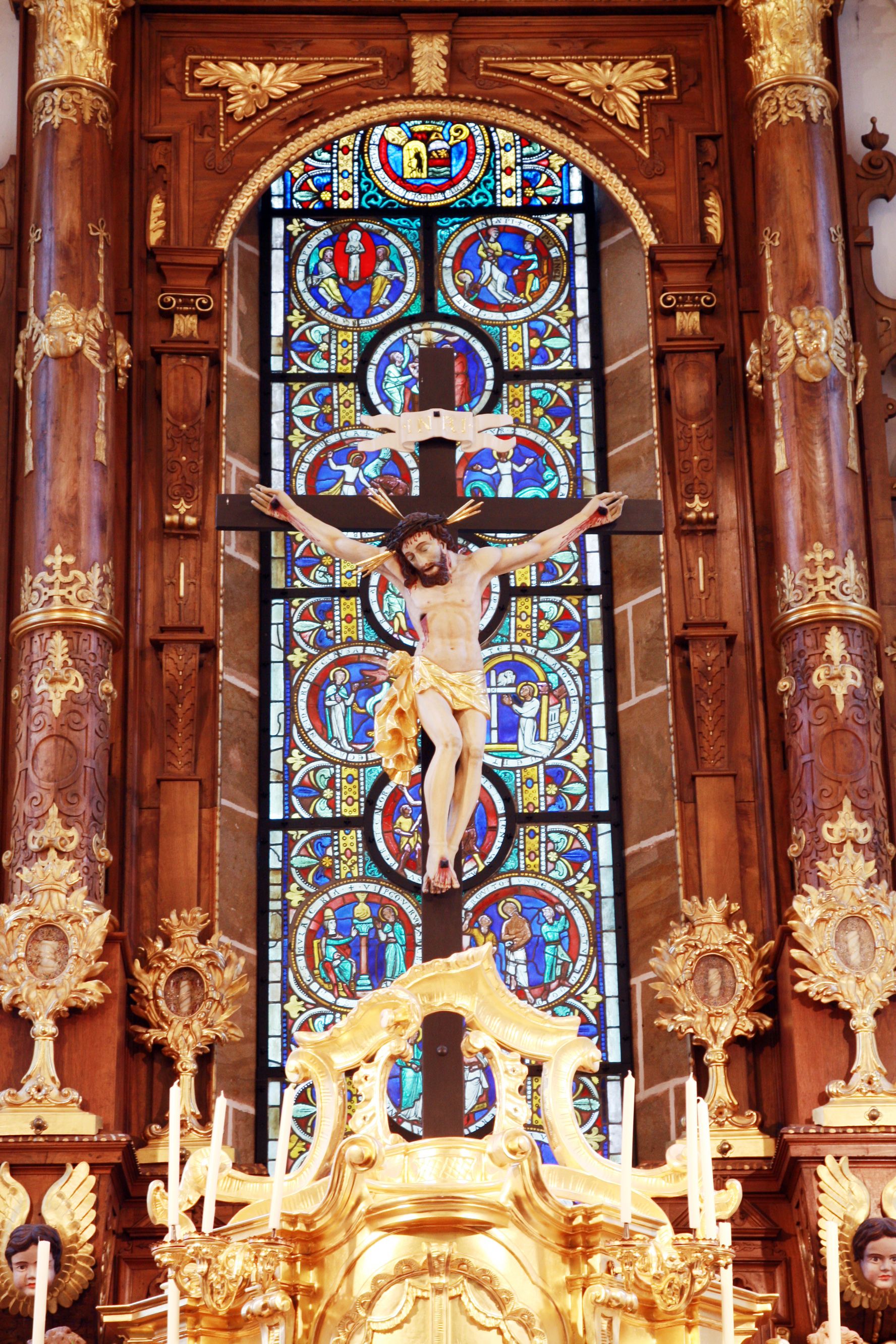 Crucifix in front of a colorful stained glass window in the collegiate church of Ardagger.