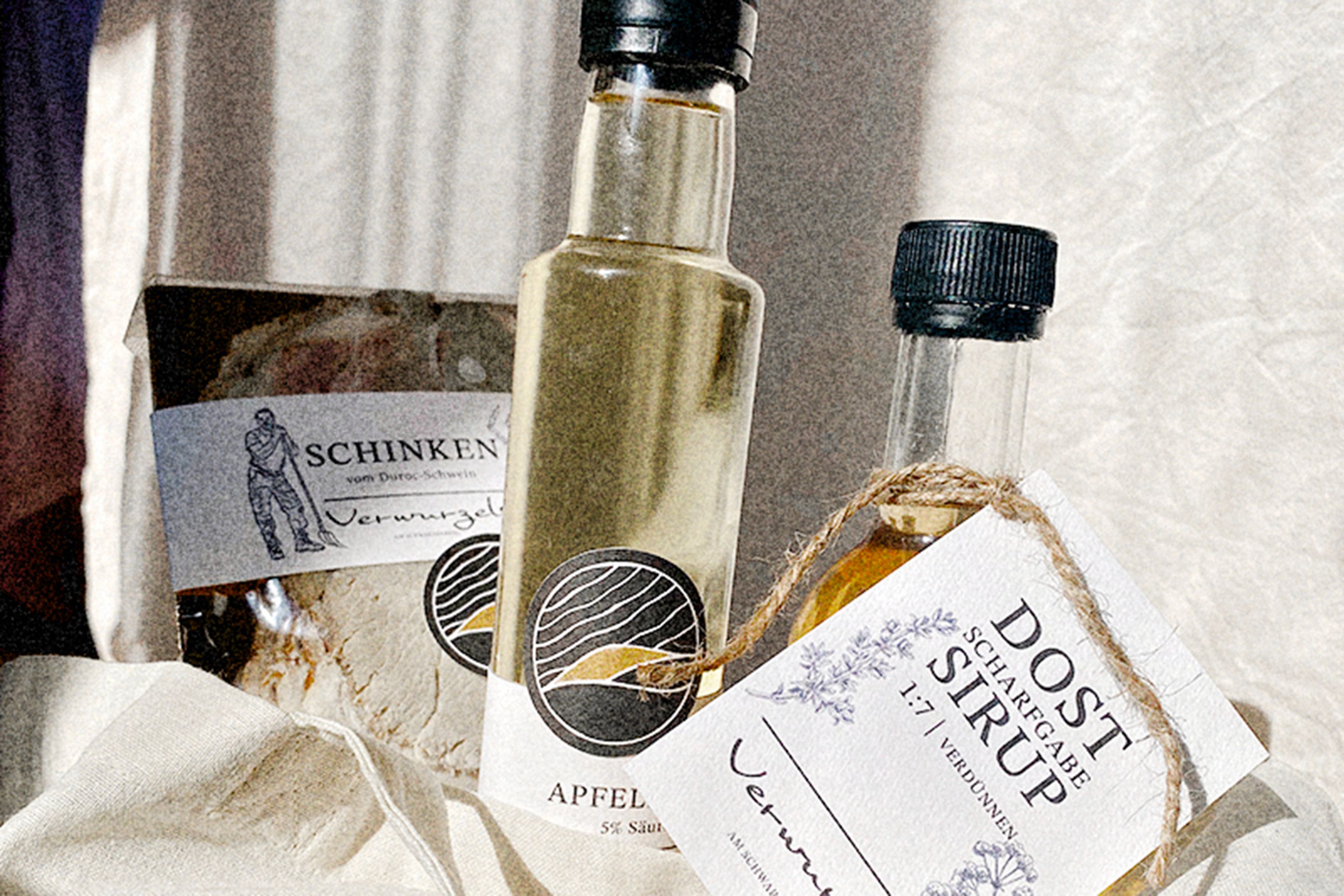 Close-up of ham, apple cider vinegar, and syrup with labels on a cloth.