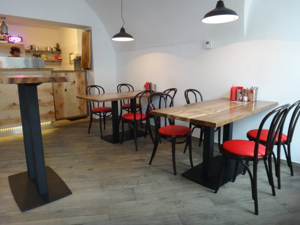 Interior view of a modern restaurant with wooden tables and red chairs.