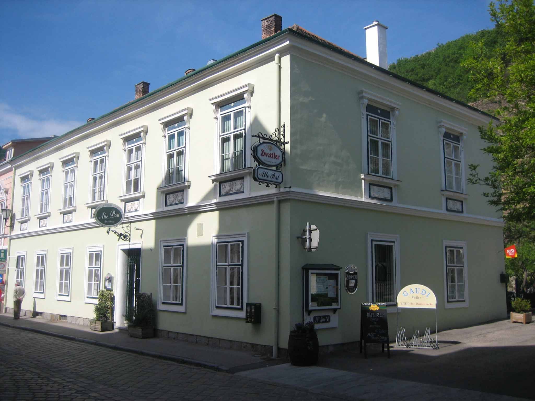 Historic building with green façade and several windows, signposted as an inn.