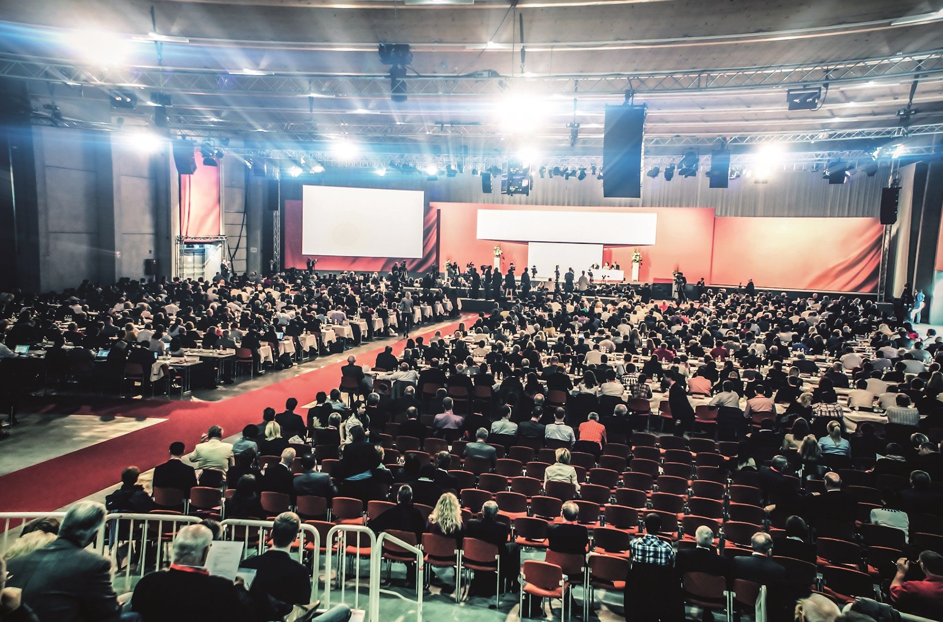 Large congress hall with many participants, stage and screen.