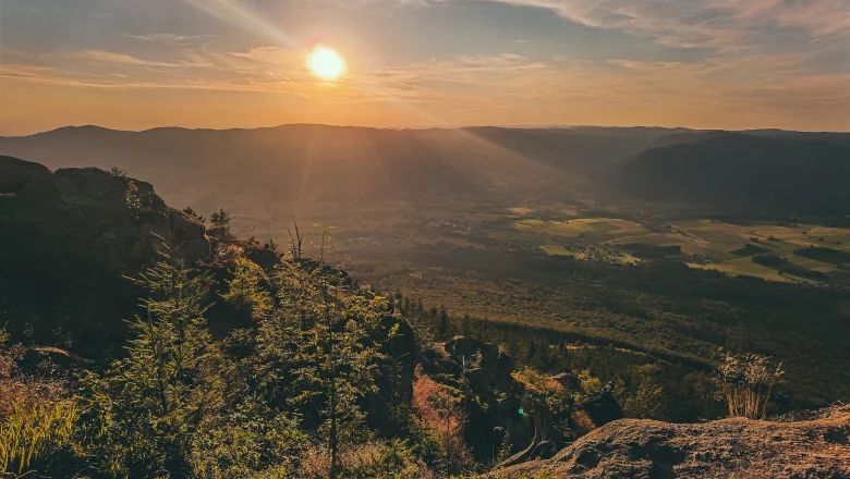 Sunset over a mountain landscape with valley and forests.