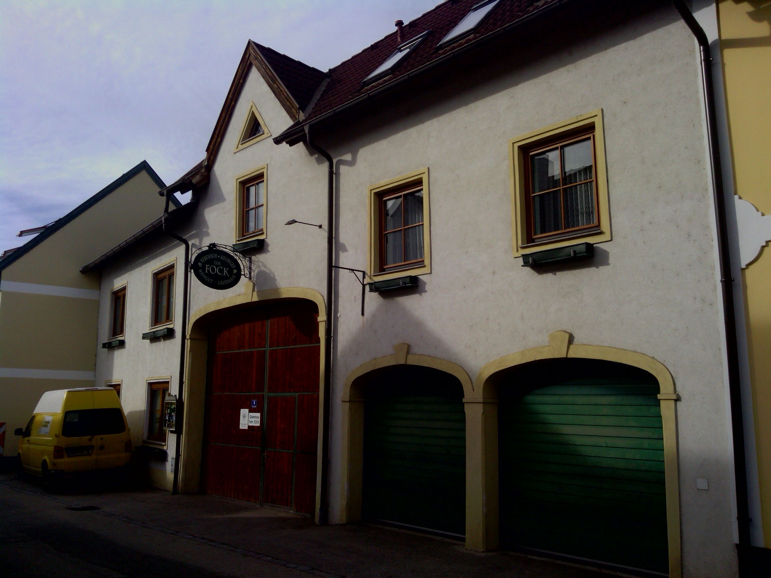 Exterior view of a building with a yellow van and green garage doors.