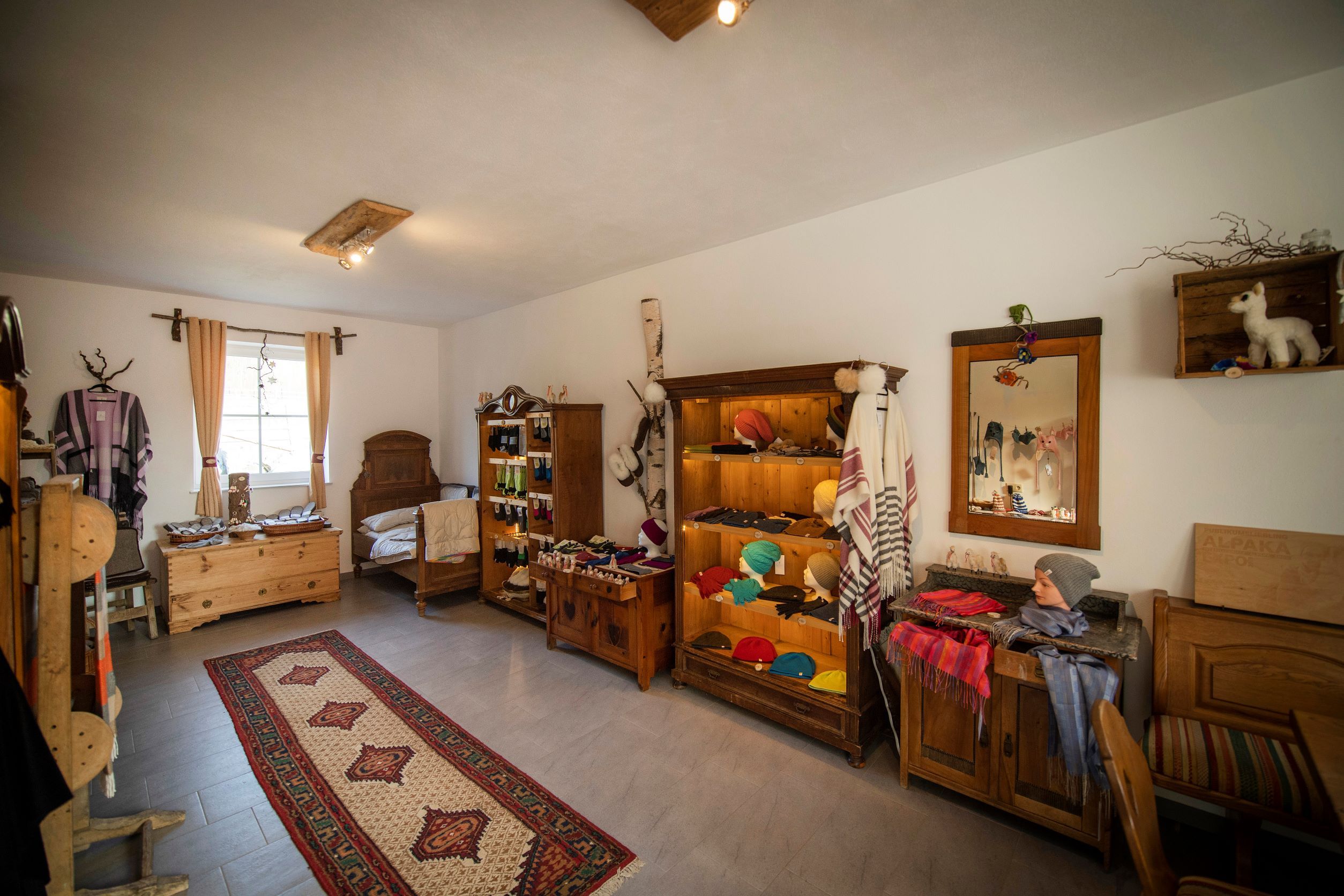 Interior view of a farm store with alpaca products, wooden furniture and carpet.