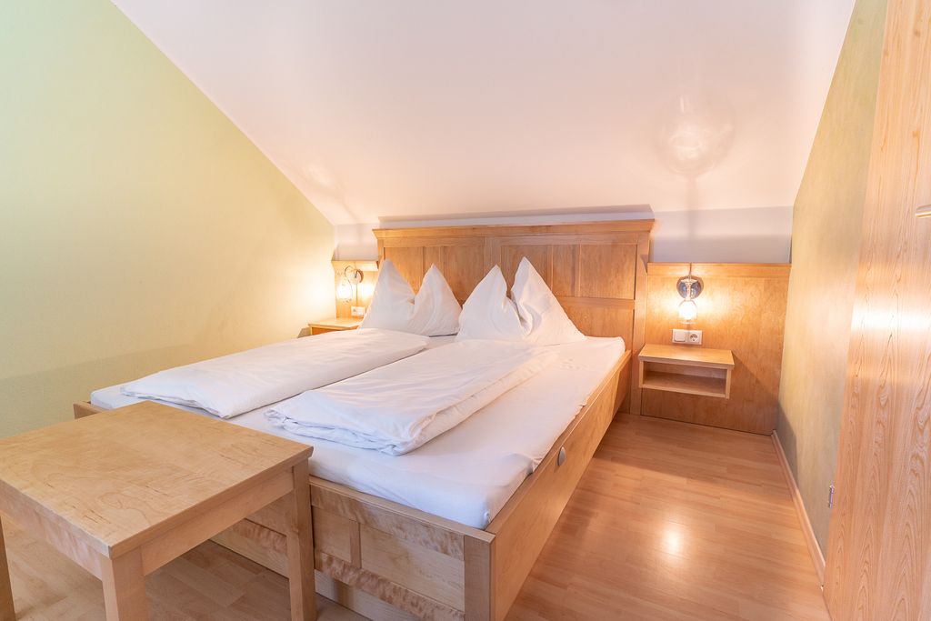Cozy bedroom with wooden furniture and double bed under a sloping roof.