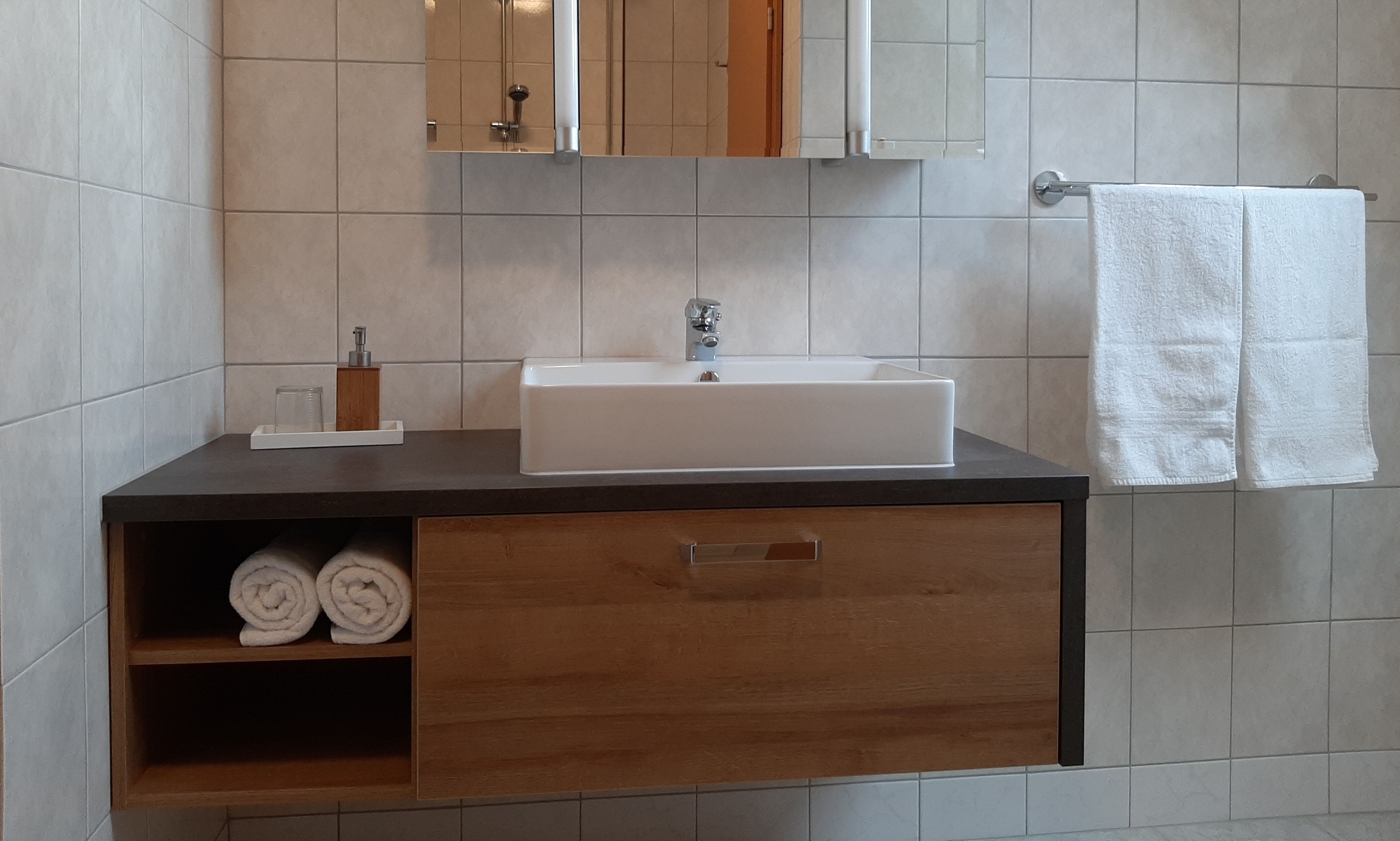 Modern bathroom with washbasin, towels and mirror.