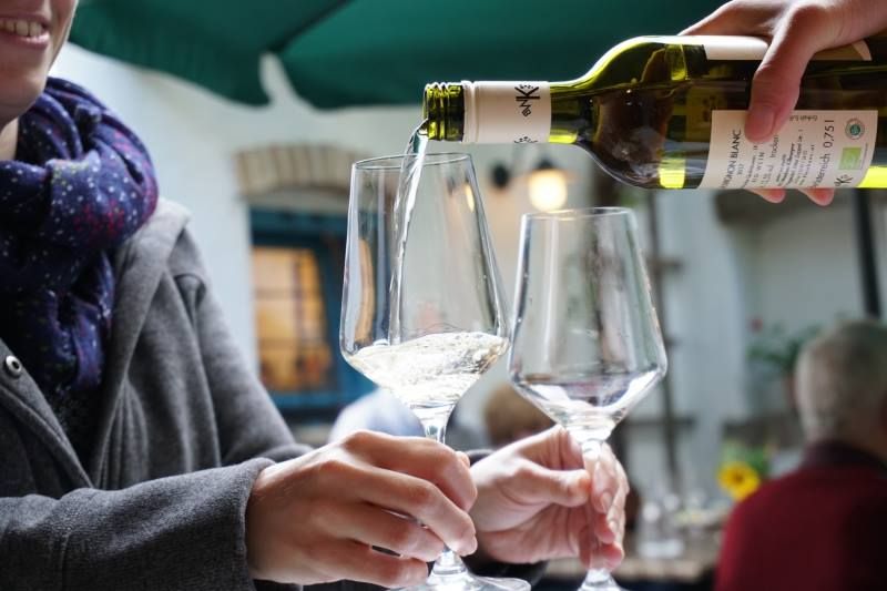 Wine is poured into a glass while one person holds it.