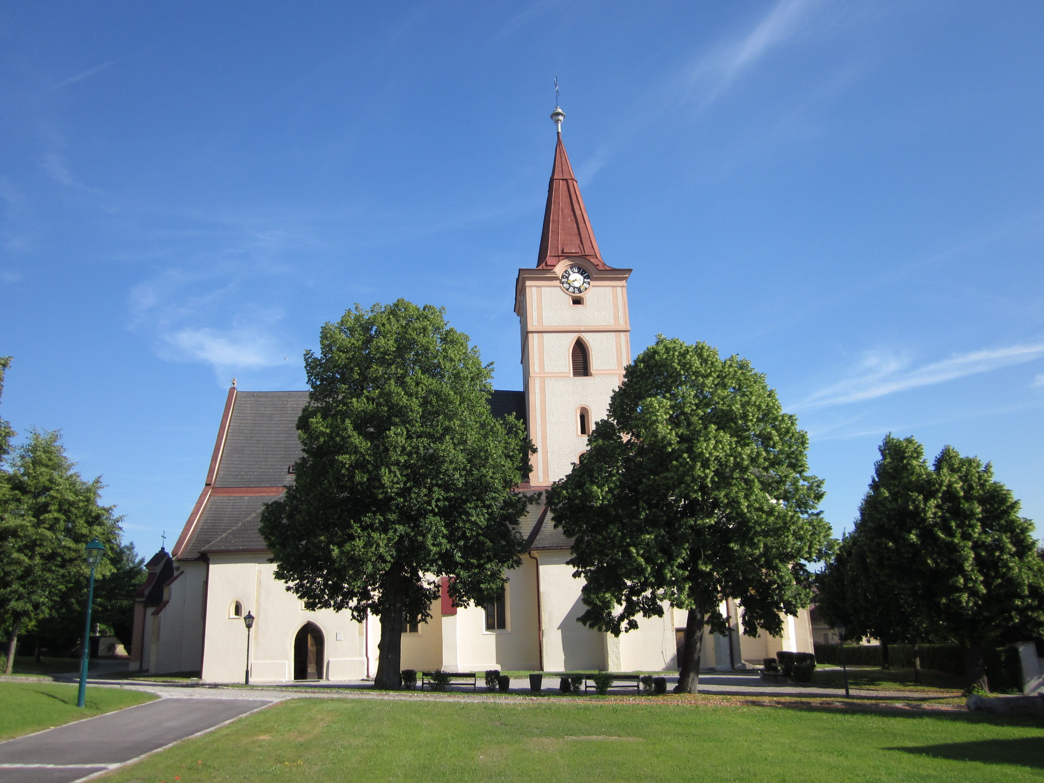 Pyhra parish church with tower and trees in the foreground.