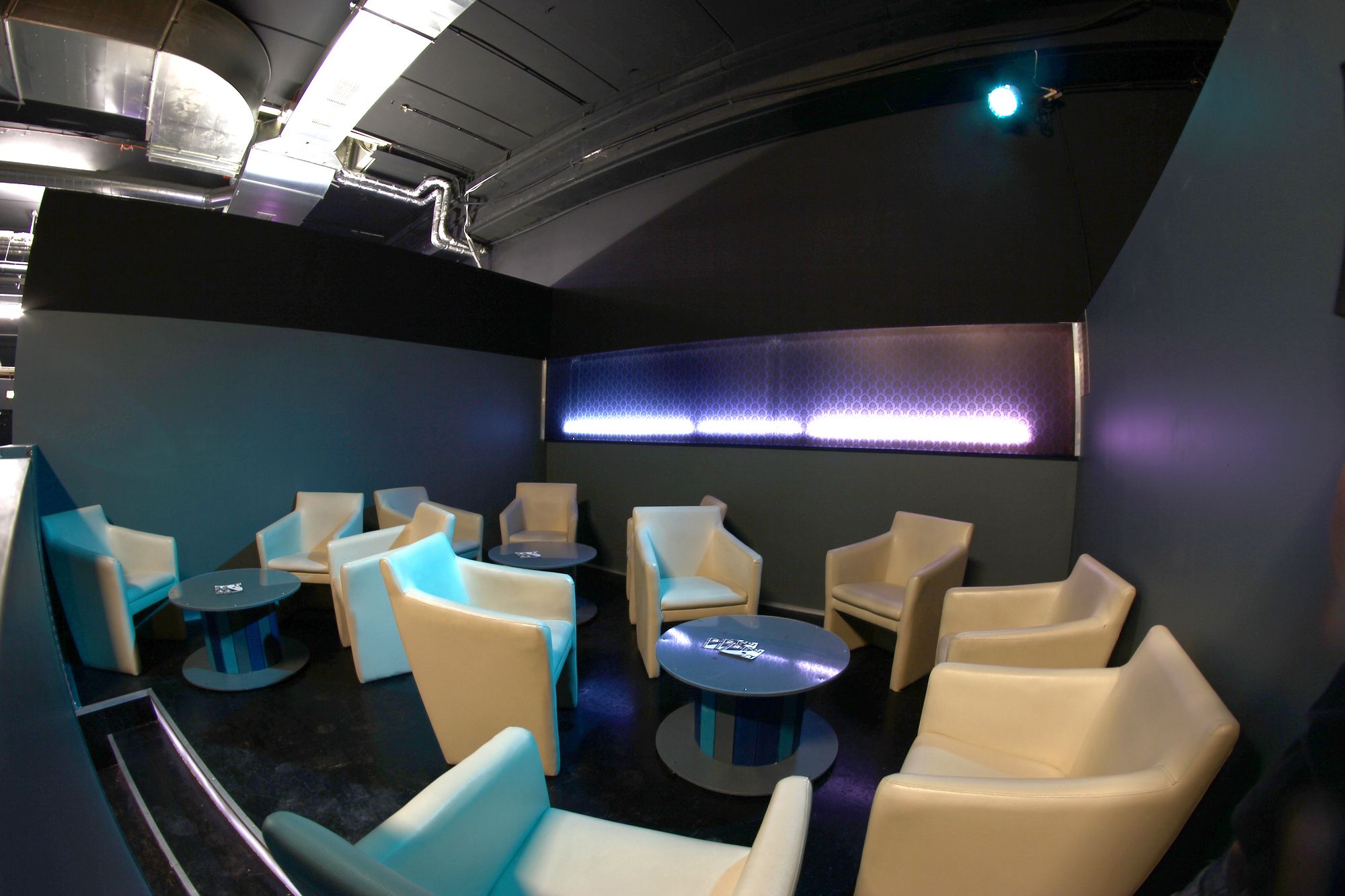 Lounge area with beige armchairs and round tables in a modern room.